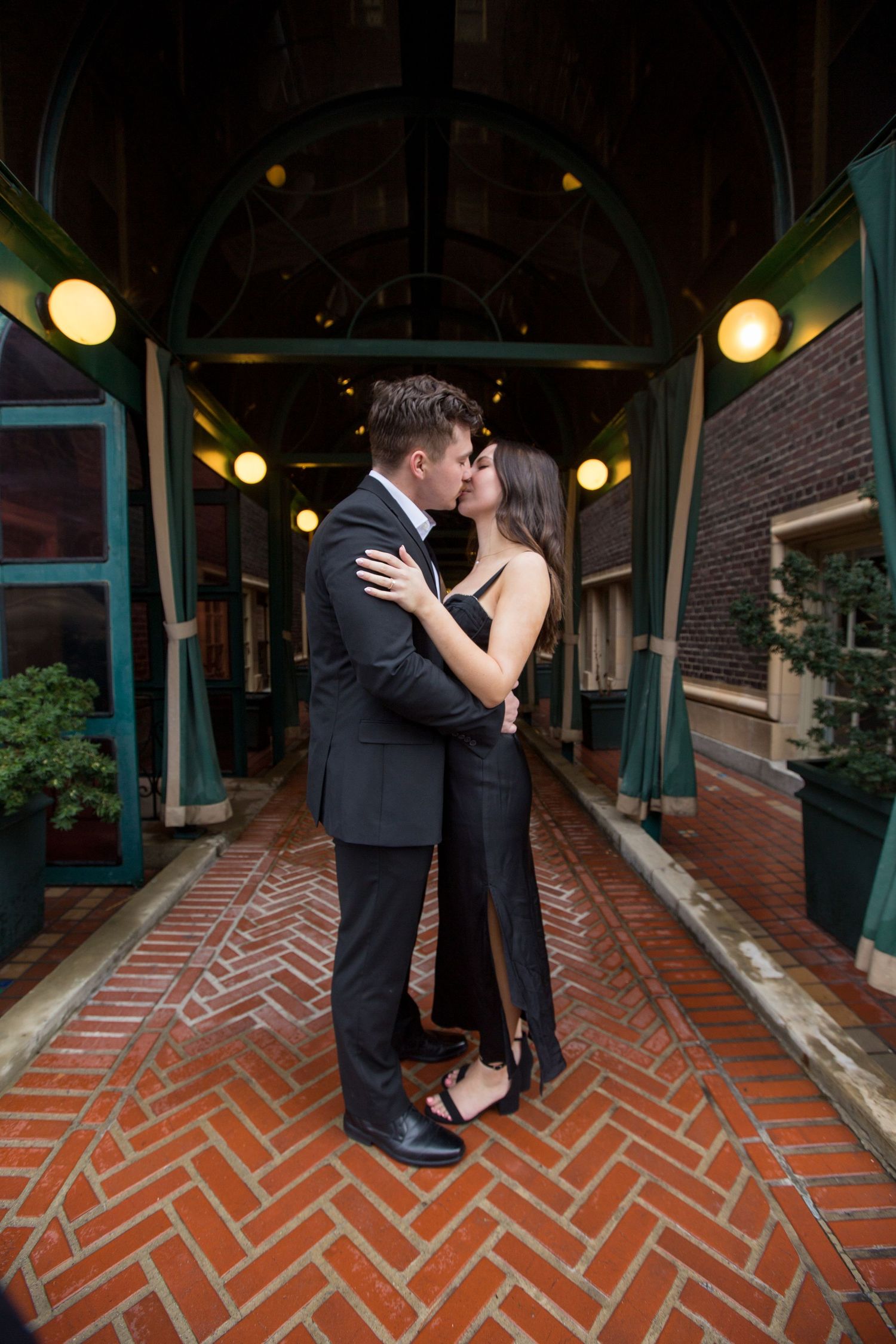 Romantic couple embracing in elegant hallway with herringbone brick floor.