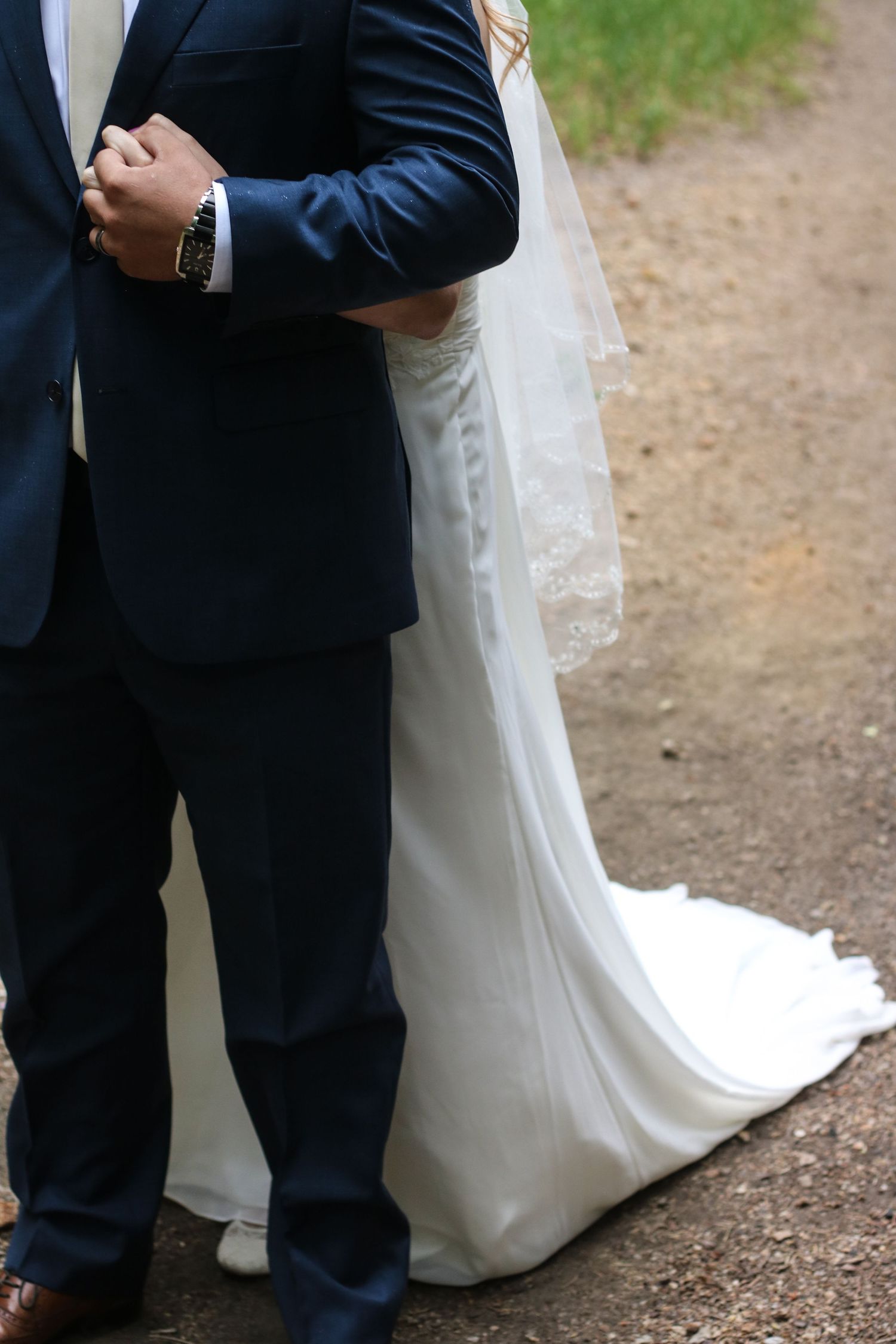 Wedding dress train details and formal attire shown in outdoor setting.