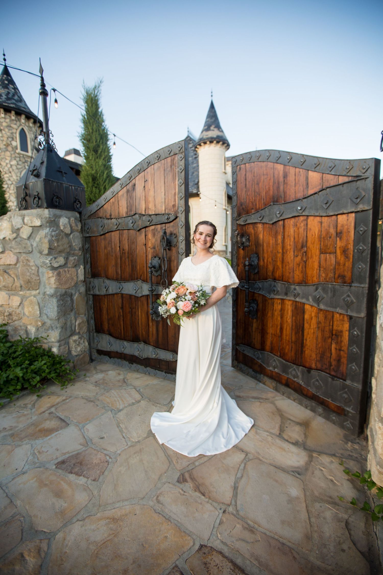 Wedding photos at castle venue with wooden gates and stone pathway.