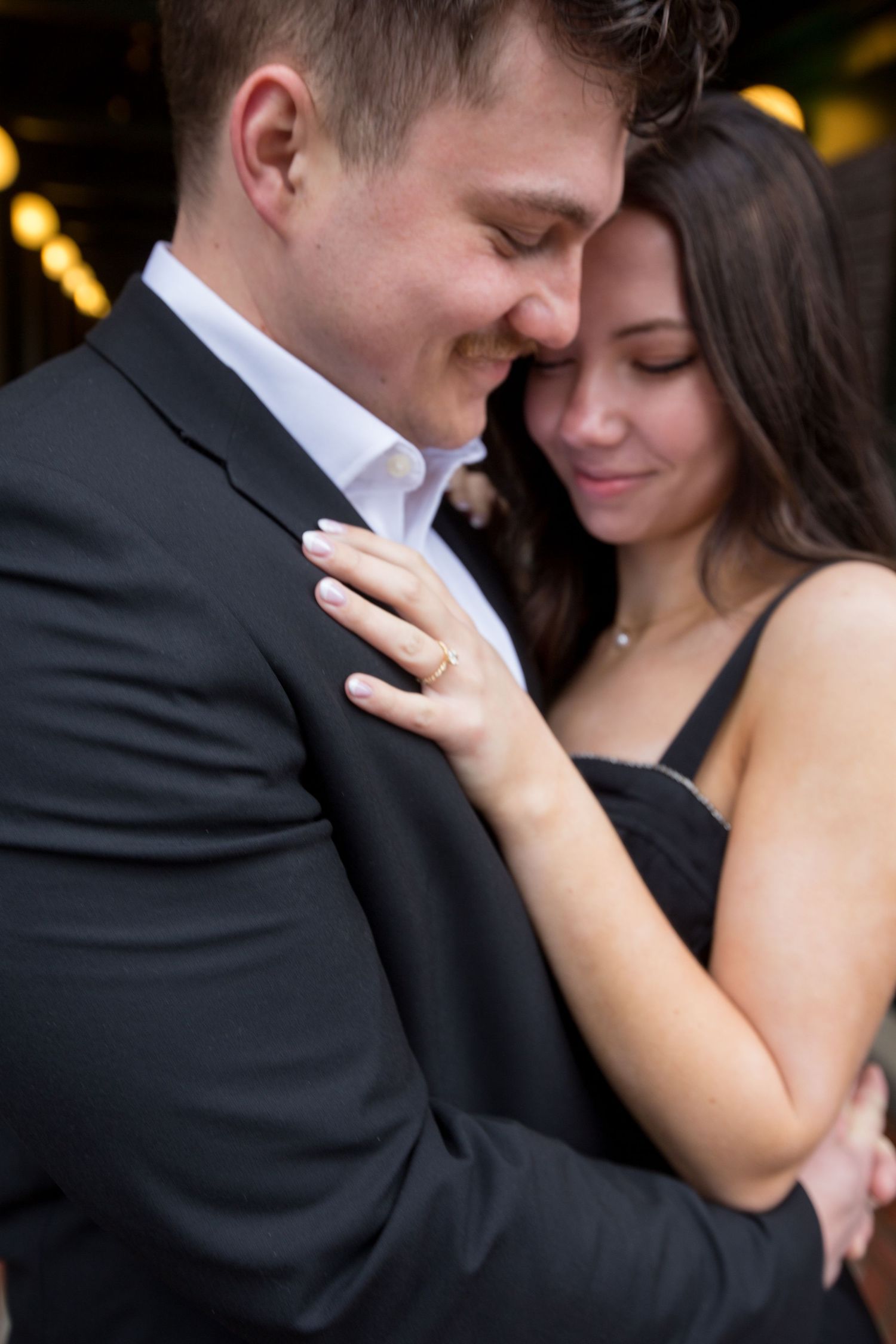 Tender moment between couple in formal wear showing engagement ring.