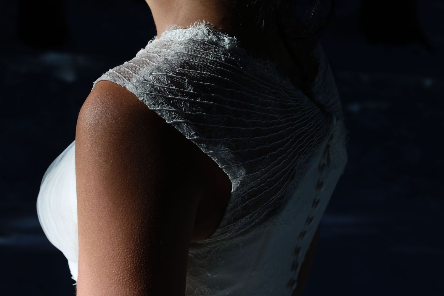 Close-up detail shot of delicate white lace and fabric from a wedding dress.