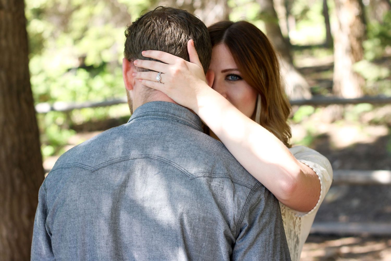 Romantic embrace captured in a sunlit wooded setting.