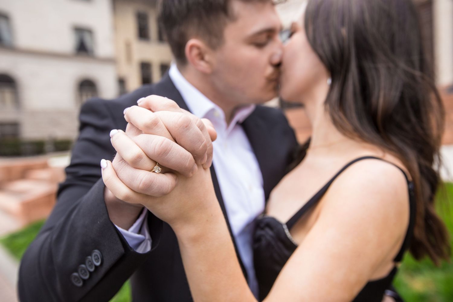Couple in formal attire dancing together outdoors in a romantic pose.