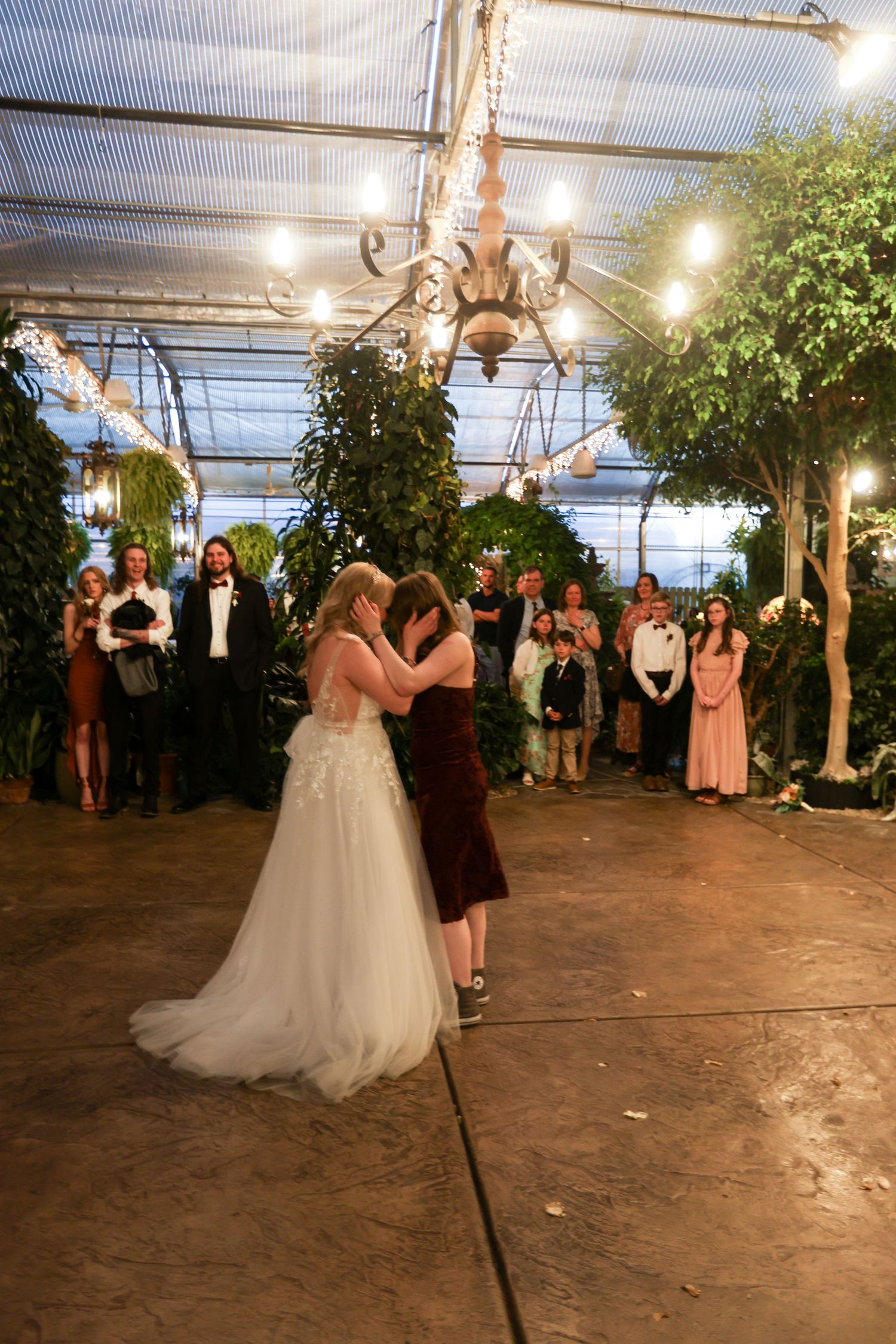 Wedding reception dancing and celebrations inside a greenhouse venue with string lights.