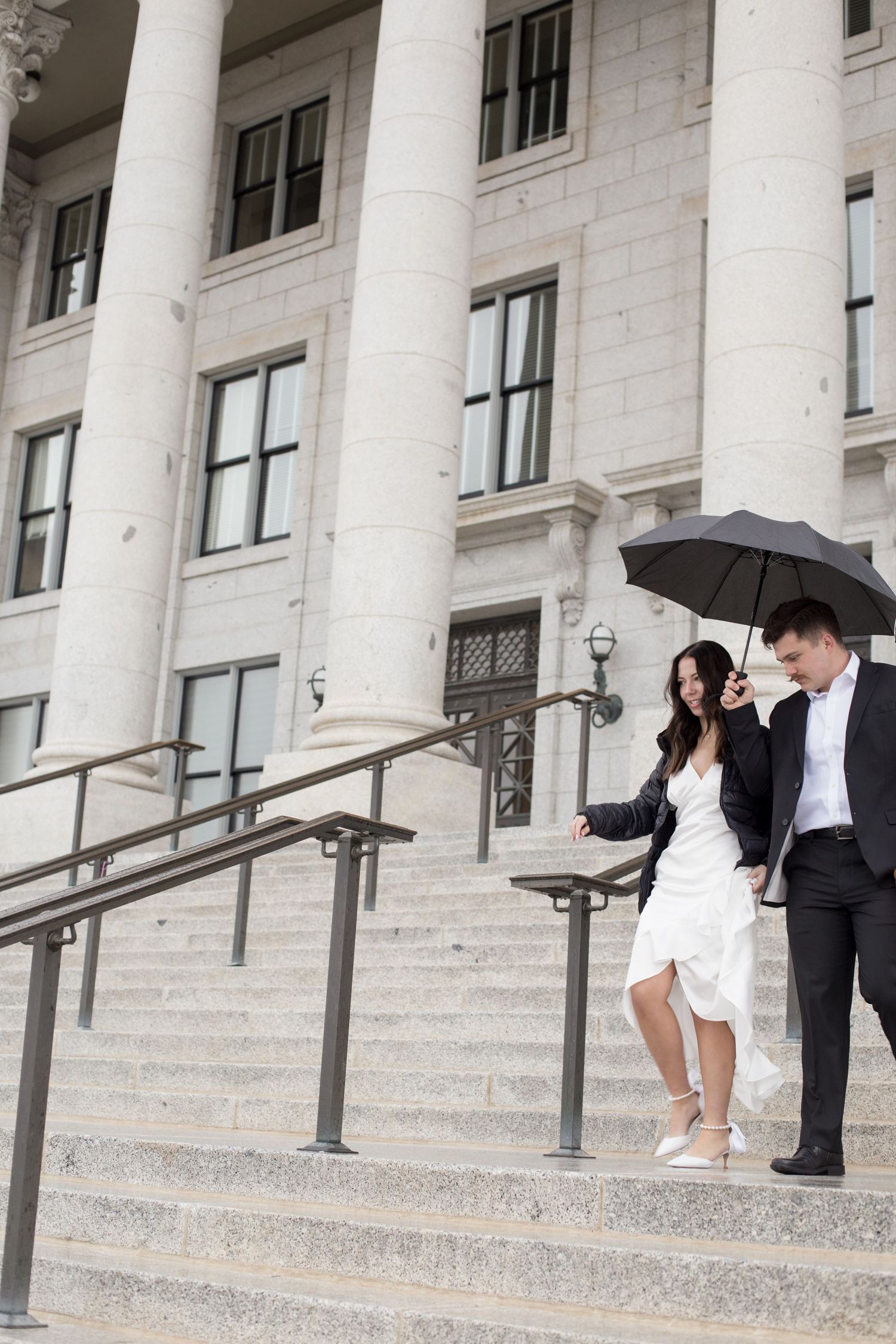 Wedding couple photographed on grand white stone steps with classical columns.