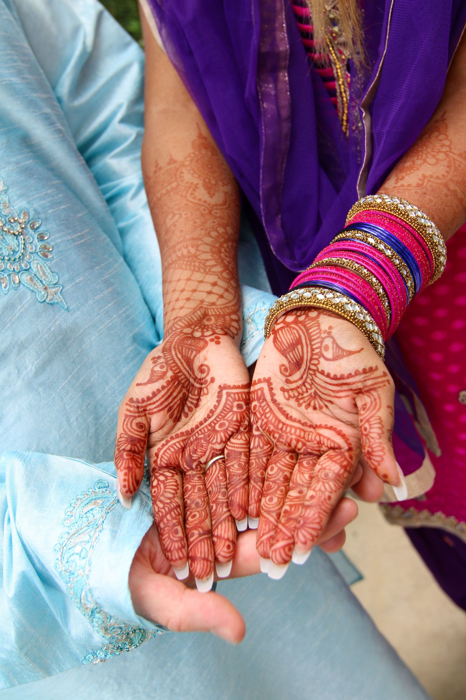 Hands adorned with intricate henna designs and colorful bangles display traditional Indian bridal decoration.