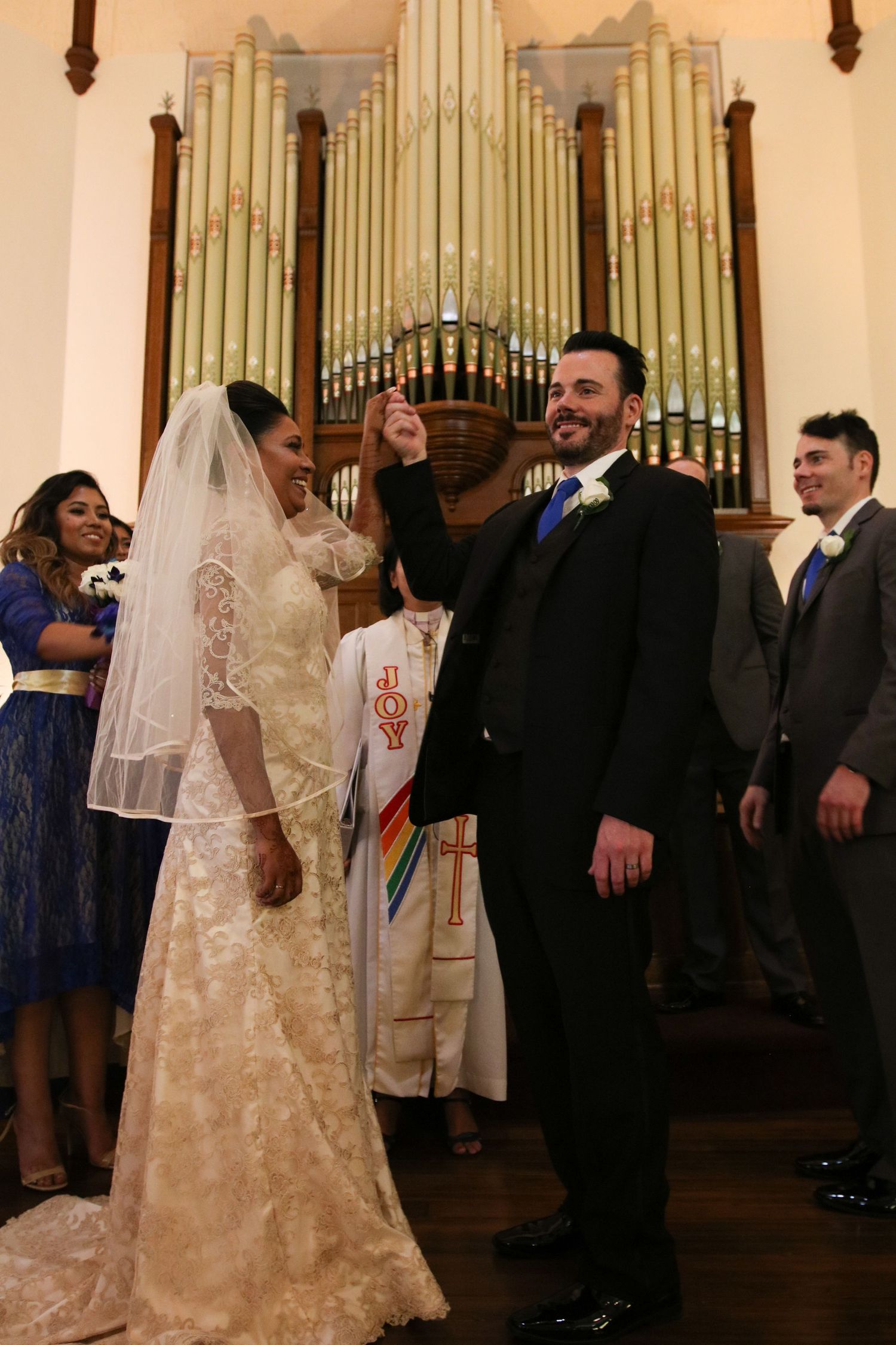 Bride and groom celebrate at church altar with pipe organ backdrop during joyful wedding ceremony.