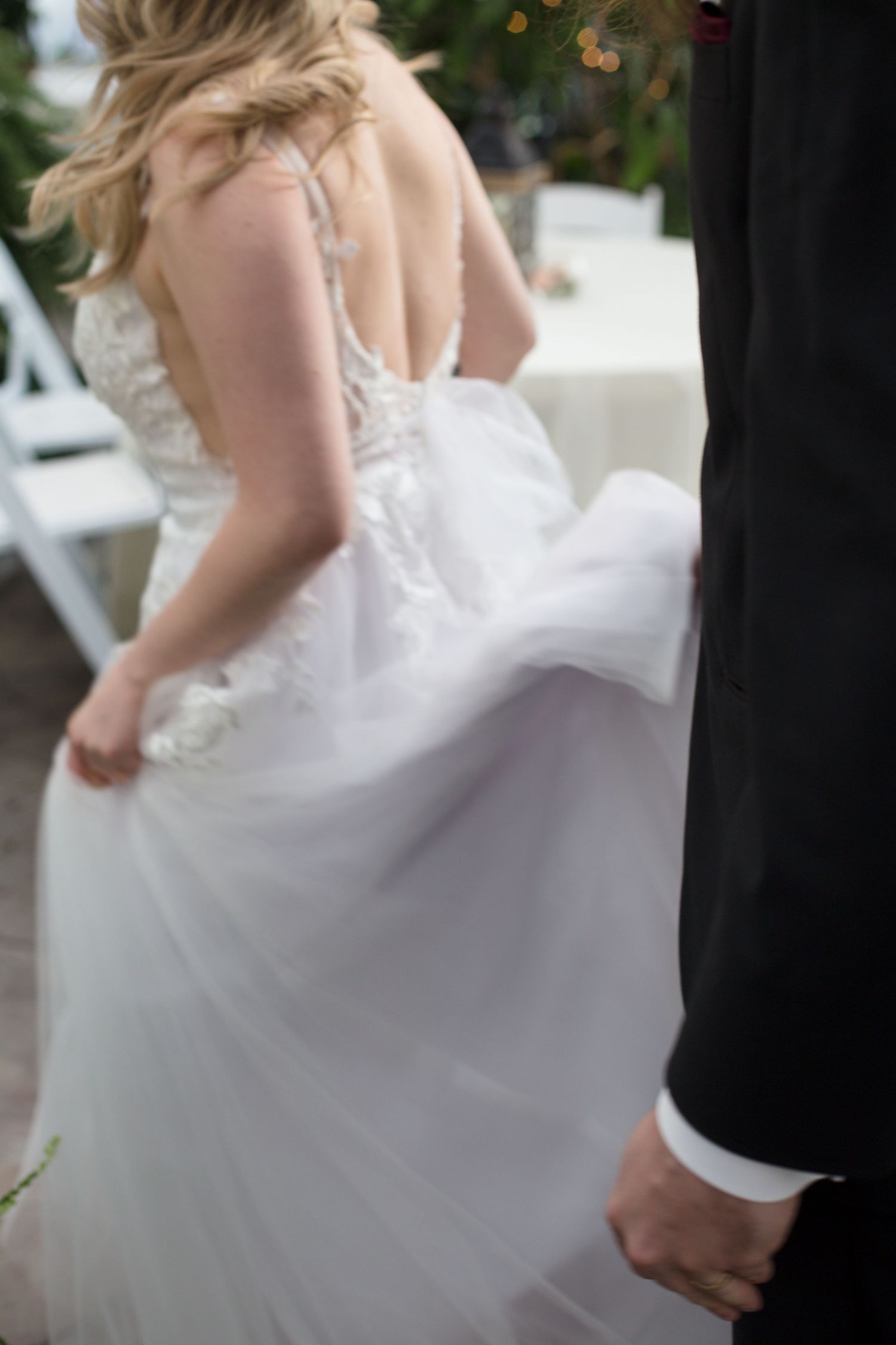Close-up of white wedding dress details during celebration.