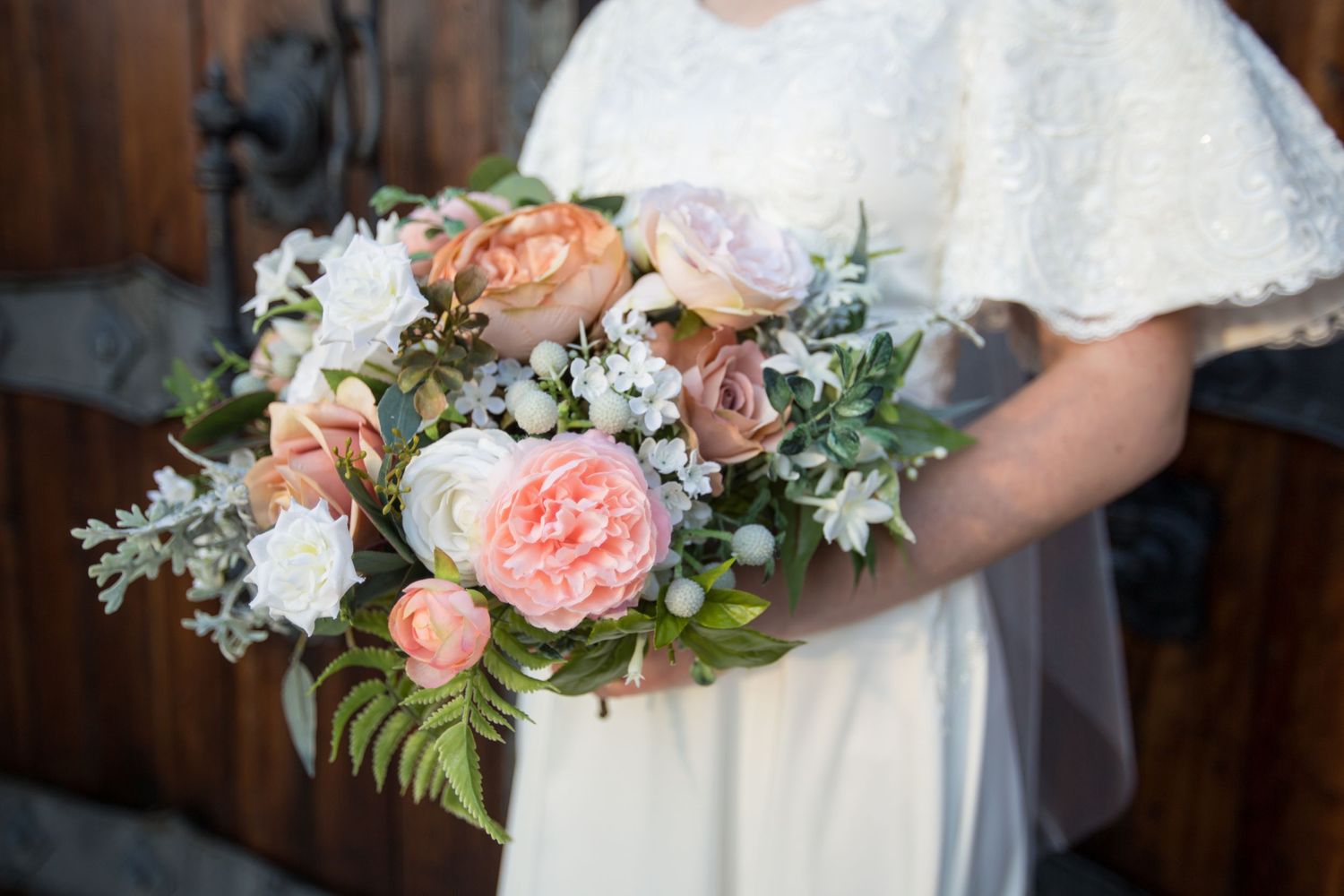 Peach and white floral bouquet with roses and greenery.