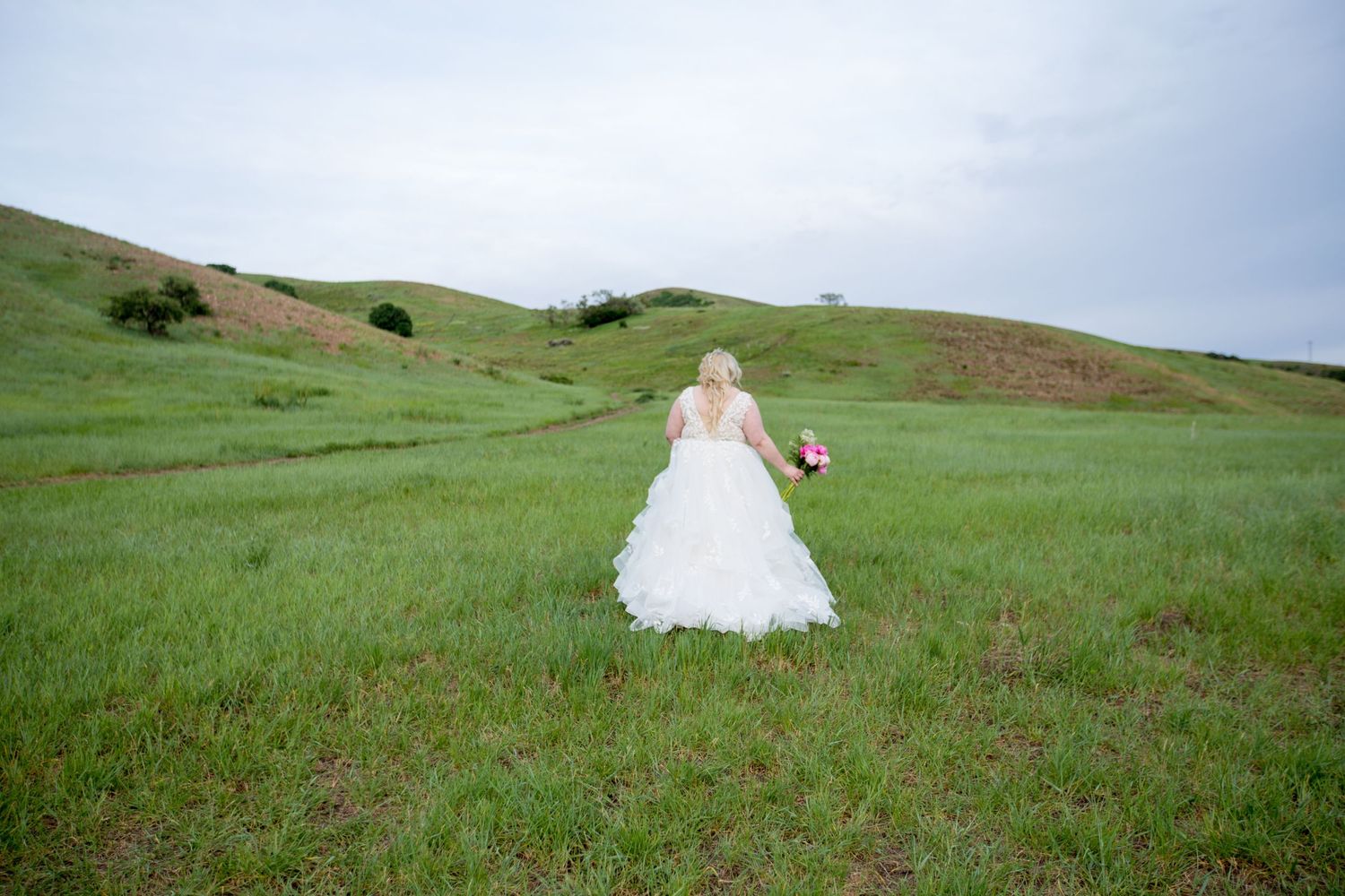 Ethereal wedding photography in a sweeping green hillside landscape.