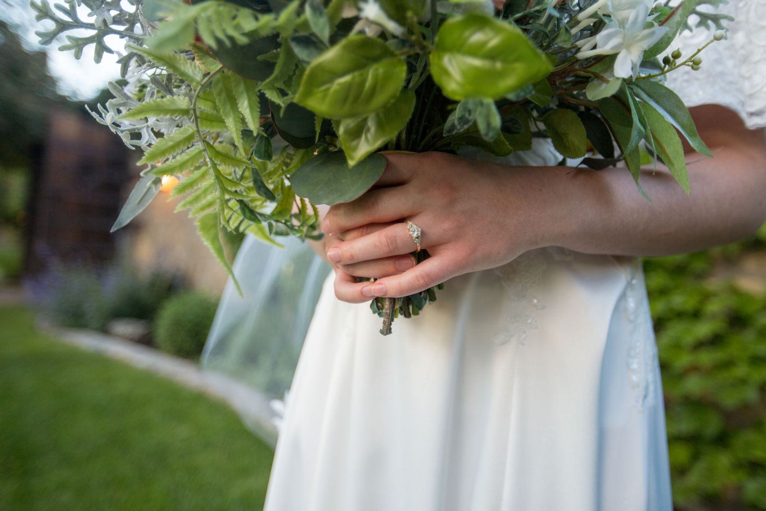Close-up of hands holding a lush bridal bouquet with pink and white flowers.