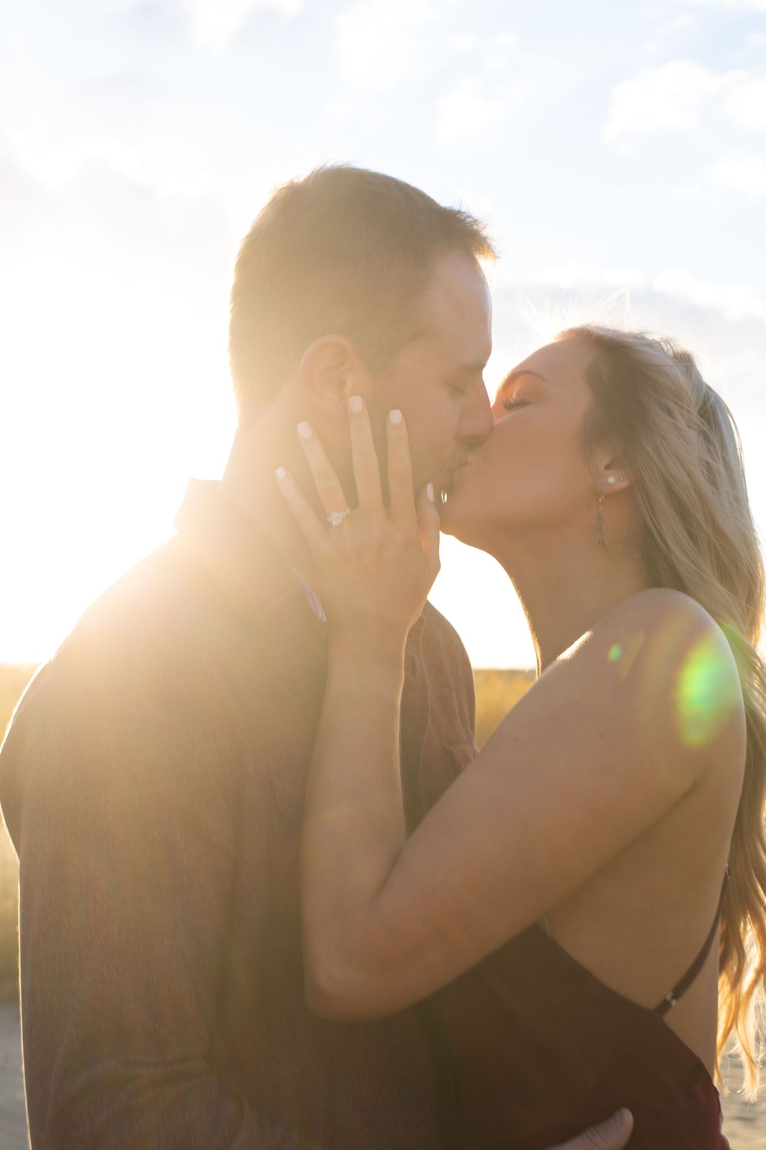 A couple sharing a romantic kiss in golden sunlight at sunset.