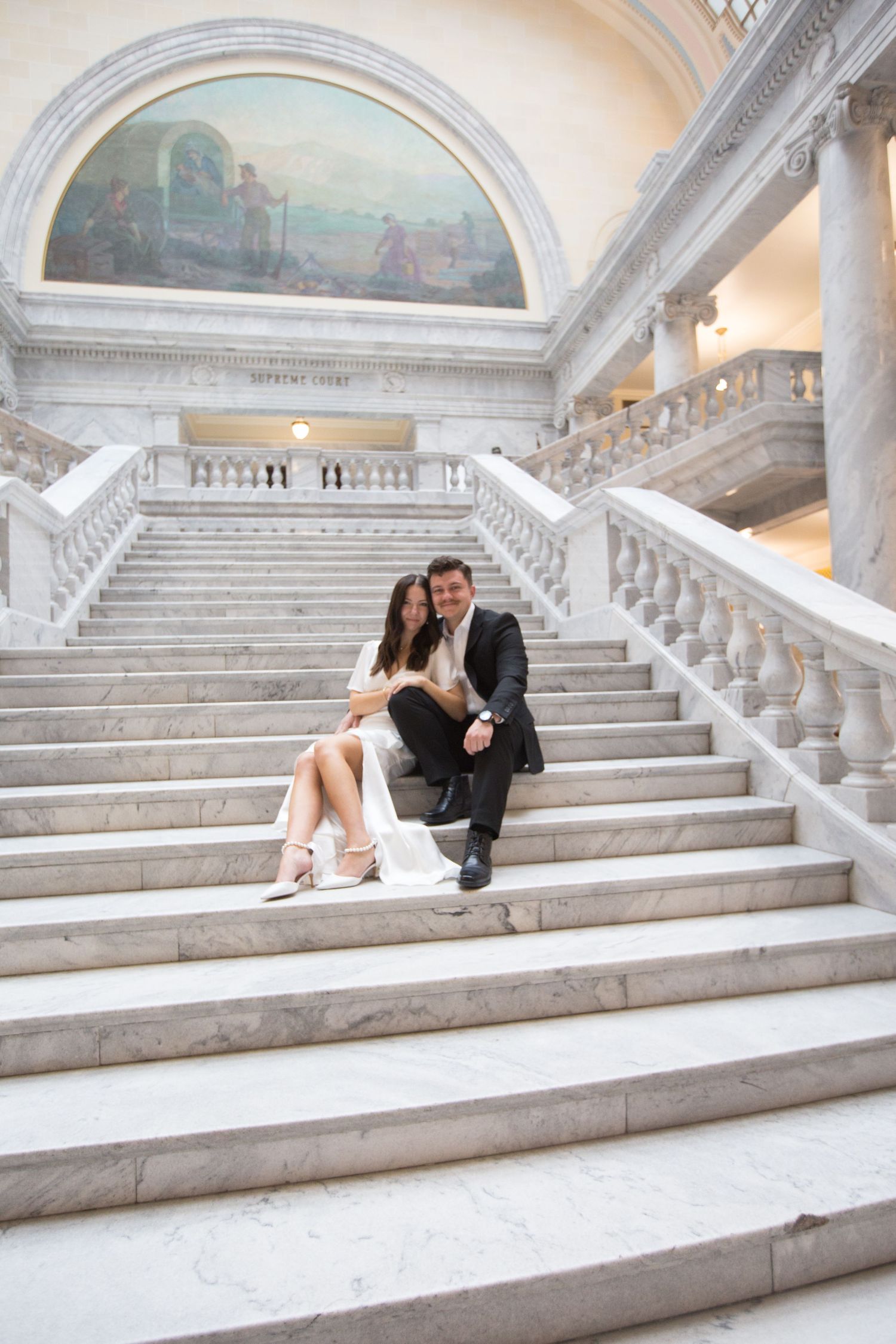 A romantic portrait on historic marble steps with classical architecture and painted murals.