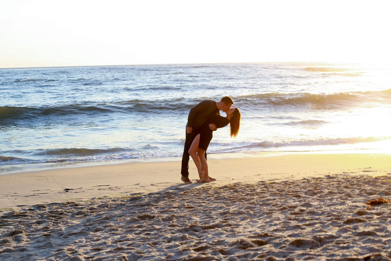 Sunset beach scene with golden light reflecting off ocean waves.