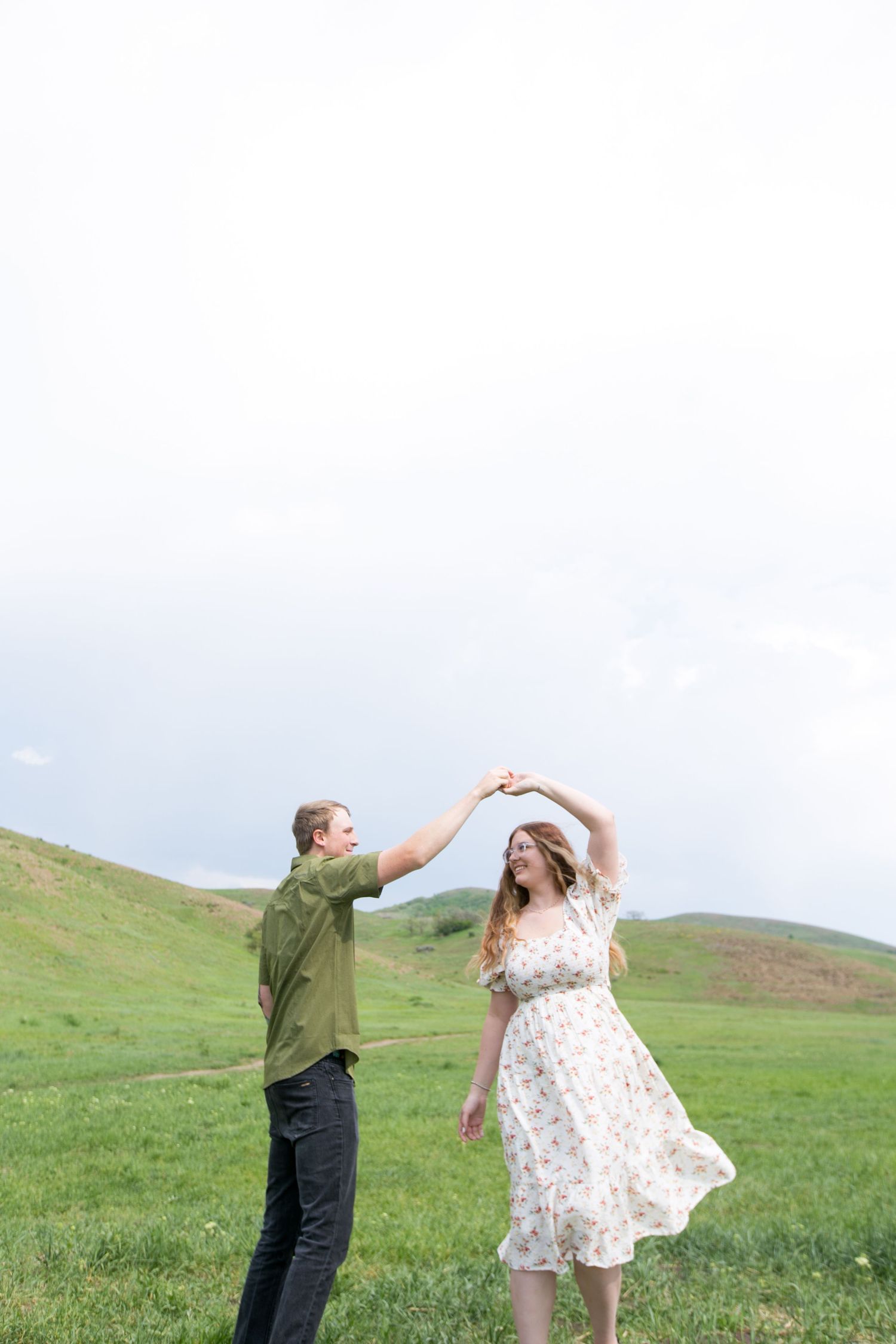 Couple dancing playfully in a grassy mountain meadow.