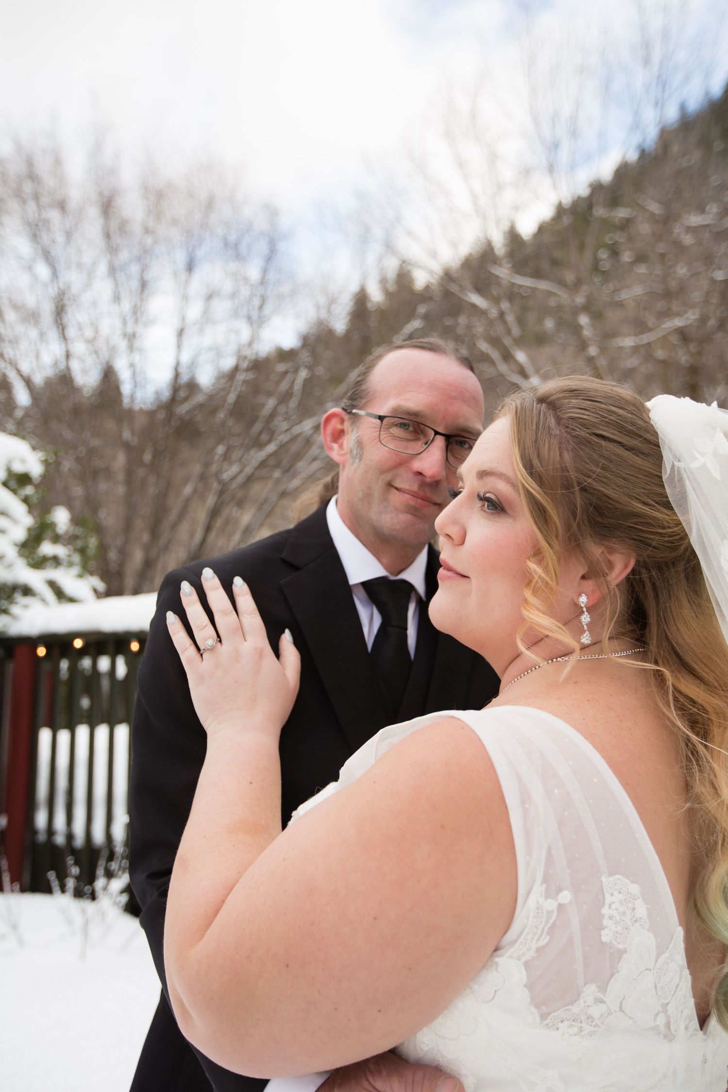 Newlyweds share an intimate moment against a snowy winter backdrop.