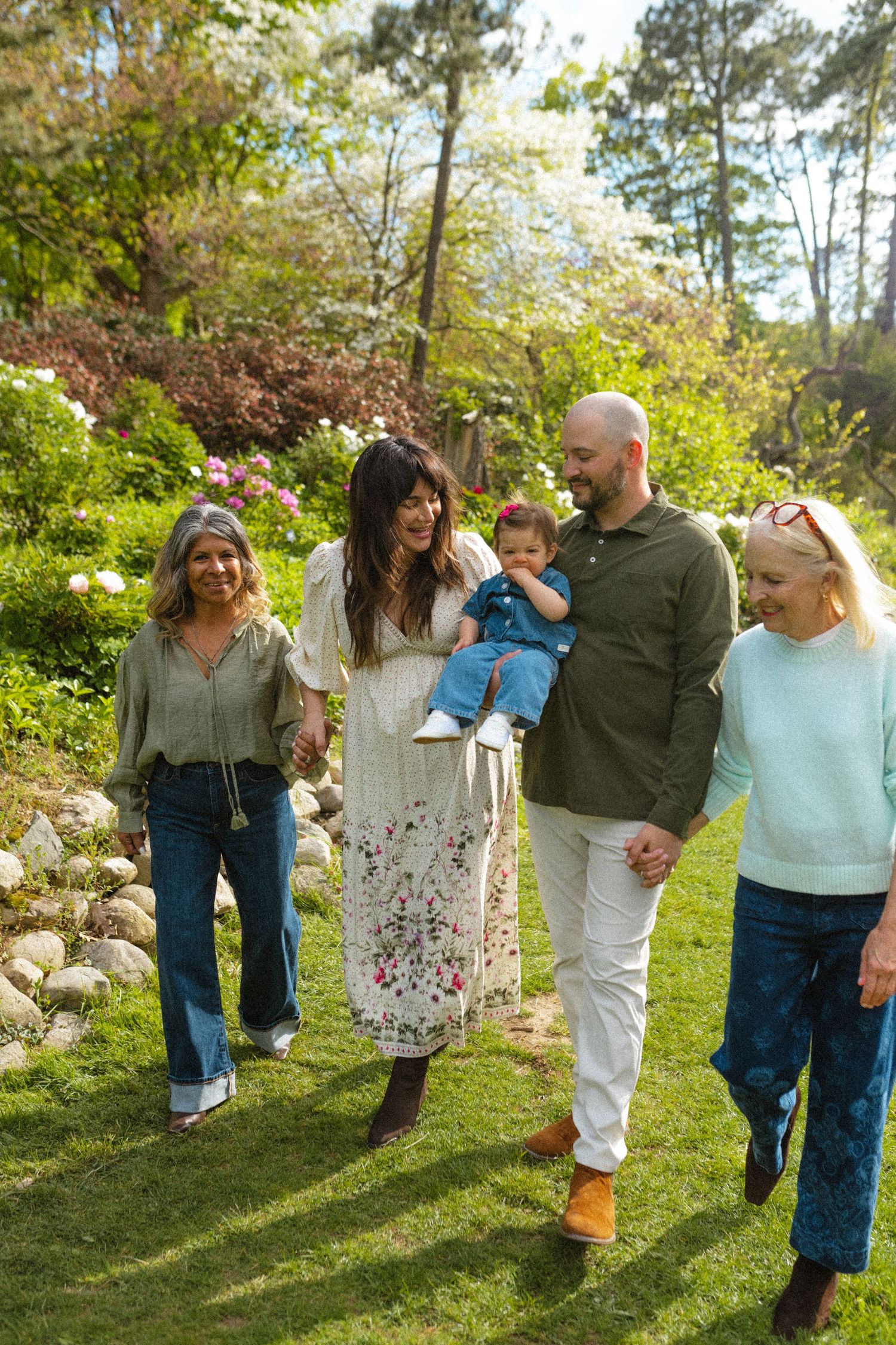 Happy multigenerational family walking together outdoors in a blooming spring garden.