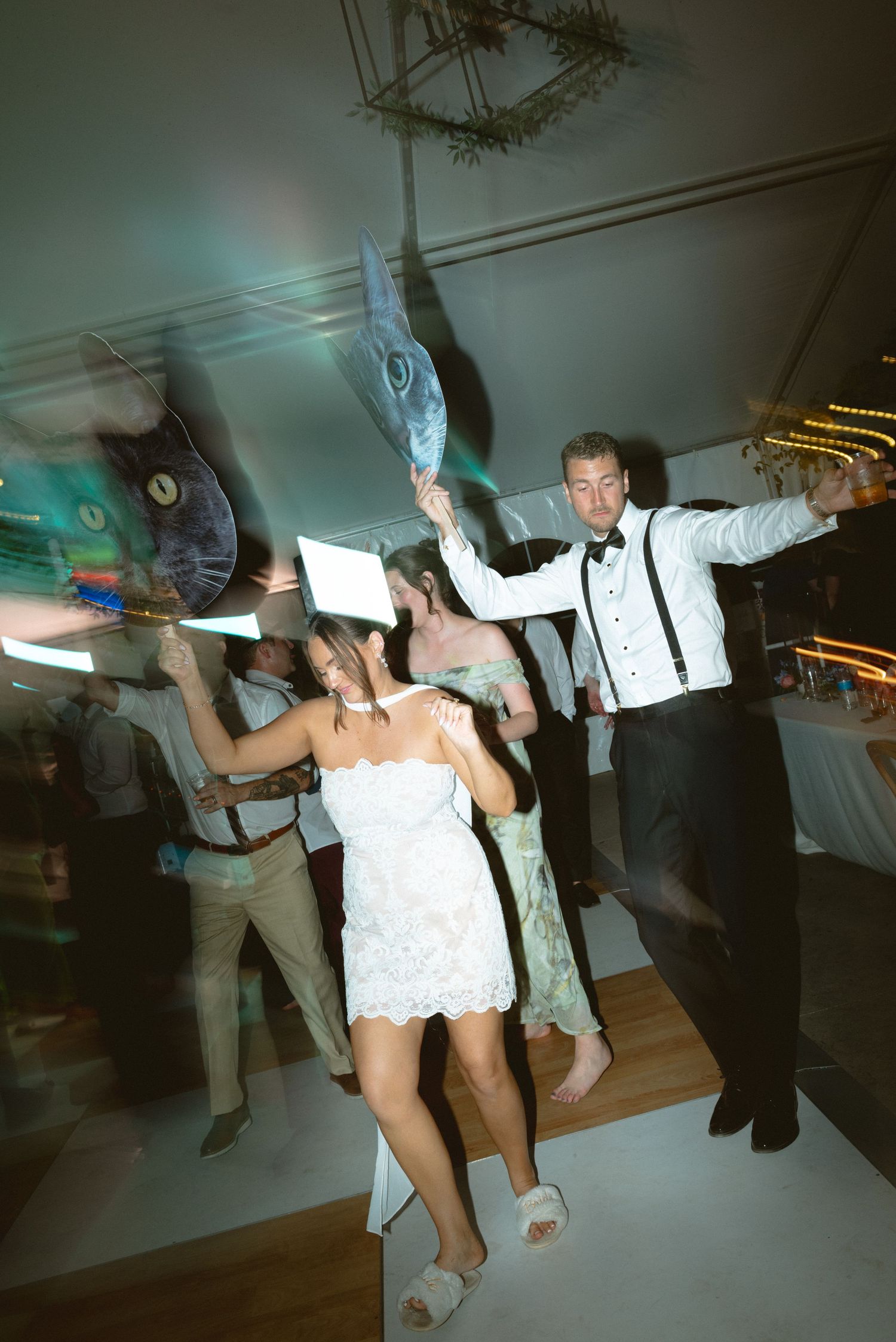 Energetic wedding reception dance floor with guests dancing and waving colorful props.