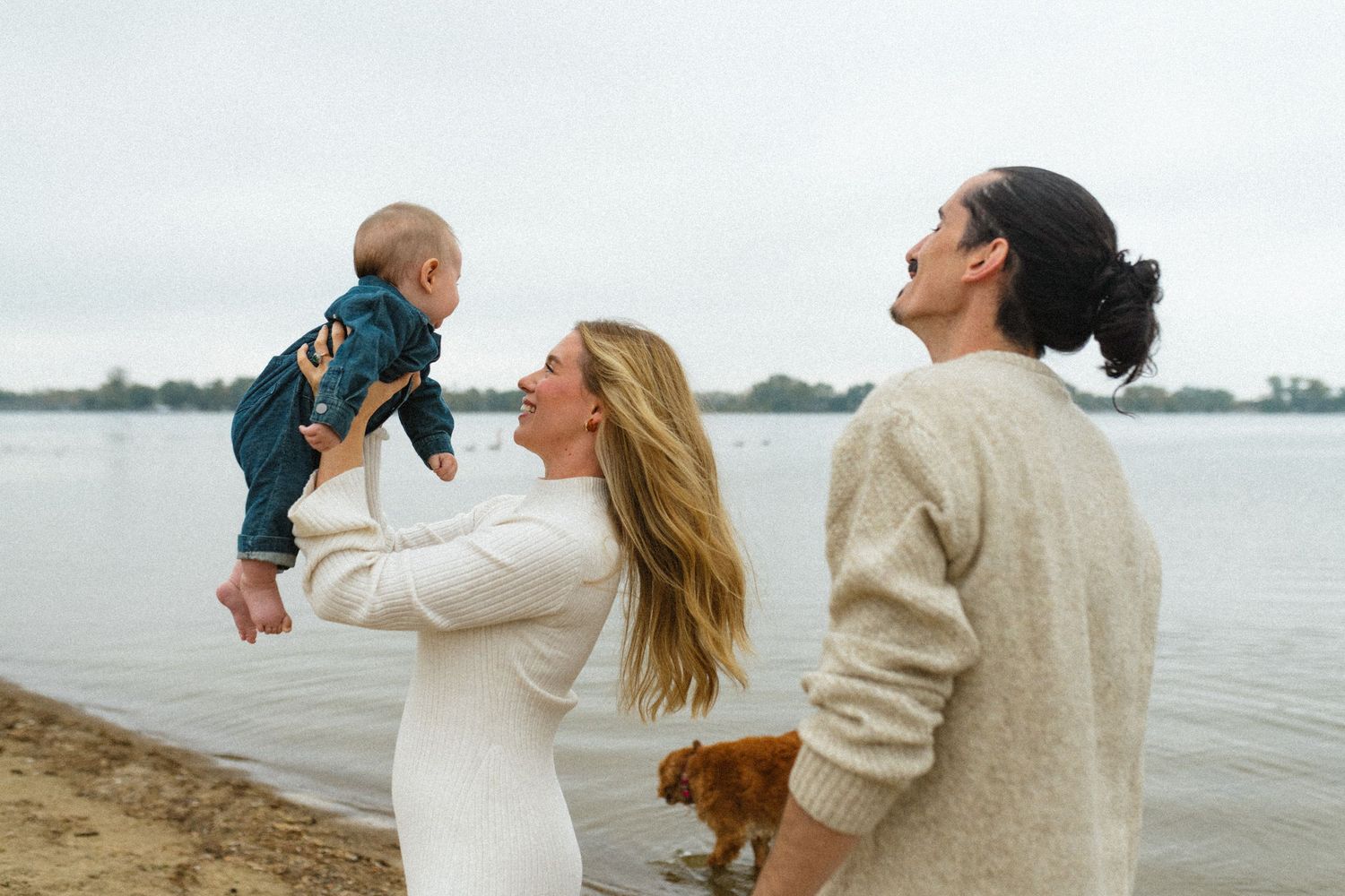 Young family with baby and dog enjoying a cloudy day by the lakeside.