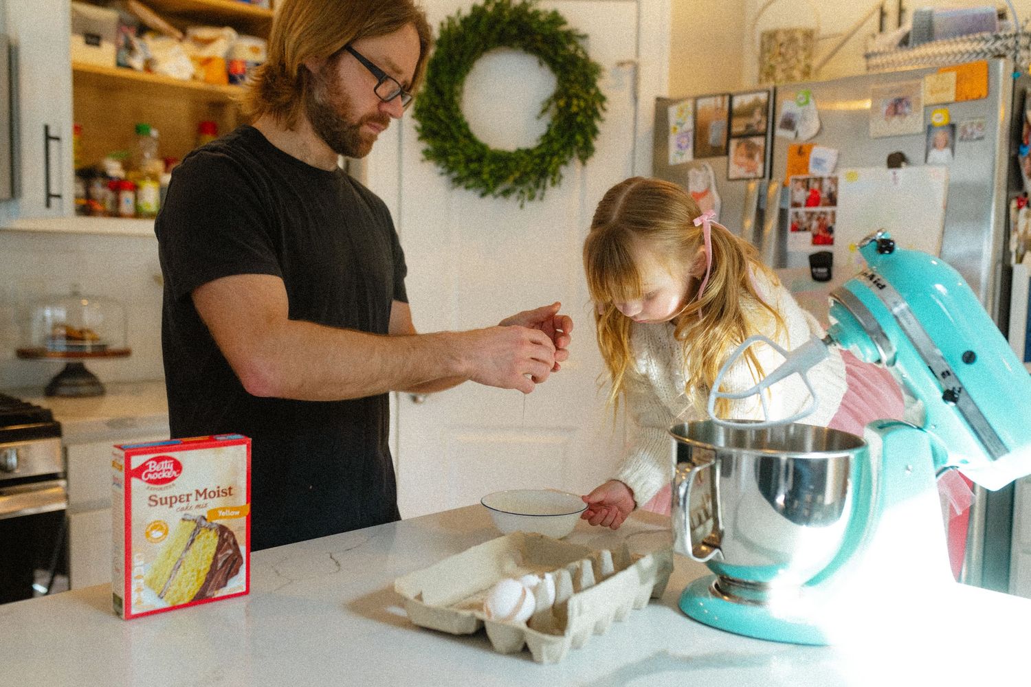 Father and daughter baking together using a Betty Crocker mix in a home kitchen.