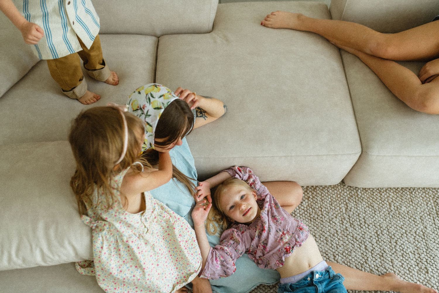 Three children playing together on a beige couch in a cozy living room.