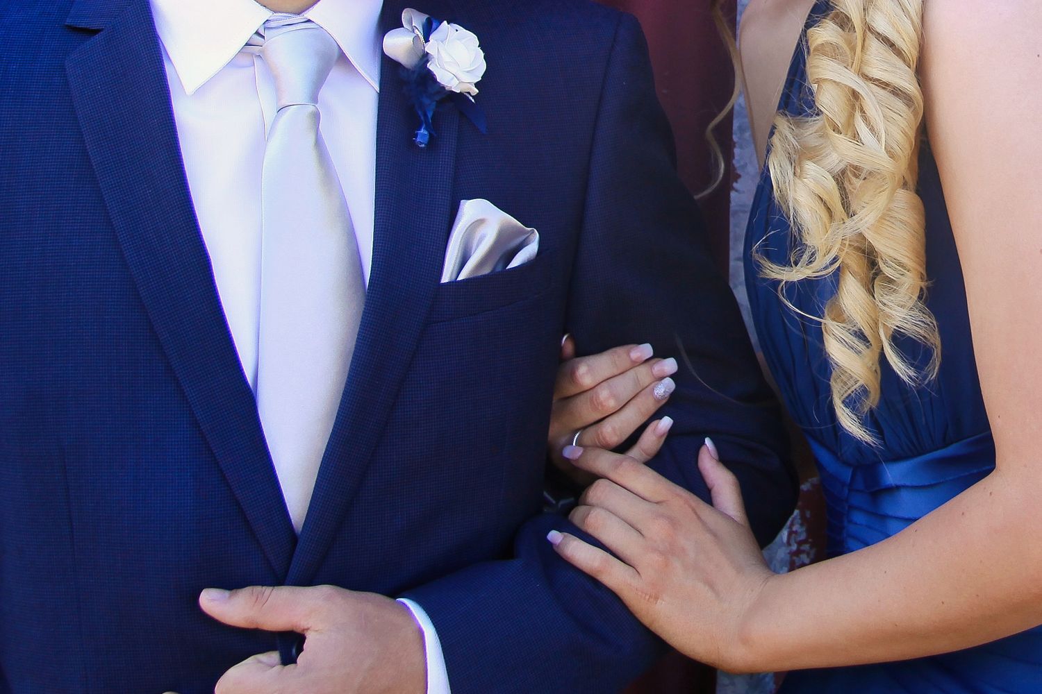 A photo showing a couple in formal attire with navy blue suits and blue colored dress.