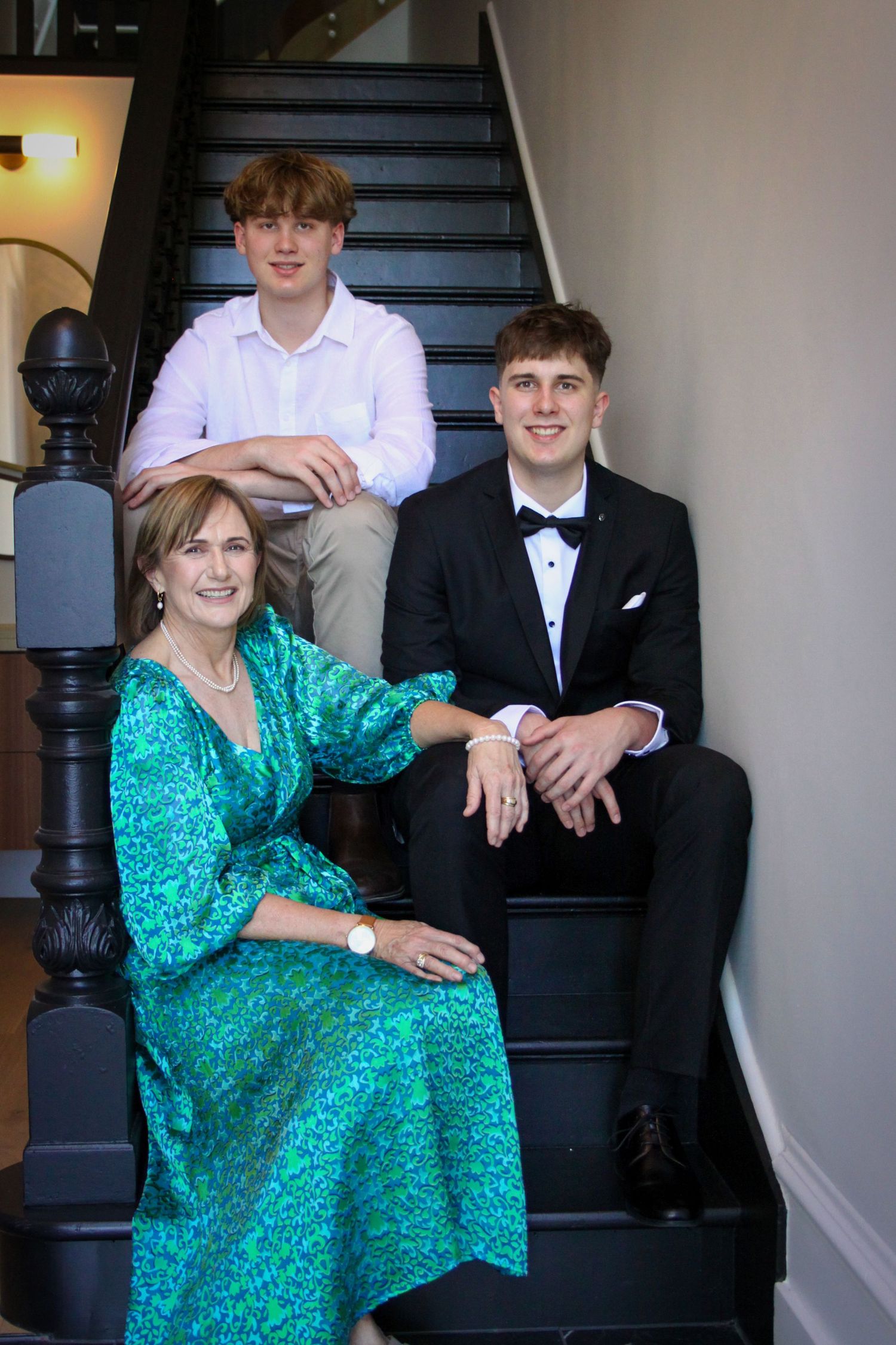 People sitting on elegant indoor staircase wearing formal attire.