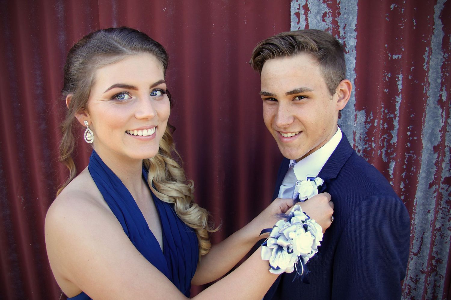 Formal couple portrait session against a rustic red metal wall background.