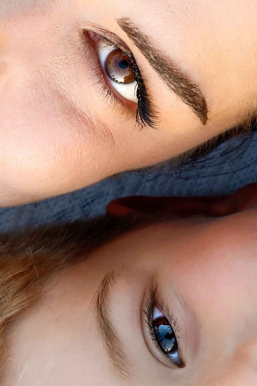 Close-up of two blue-eyed people facing each other, showcasing defined eyebrows and long lashes.