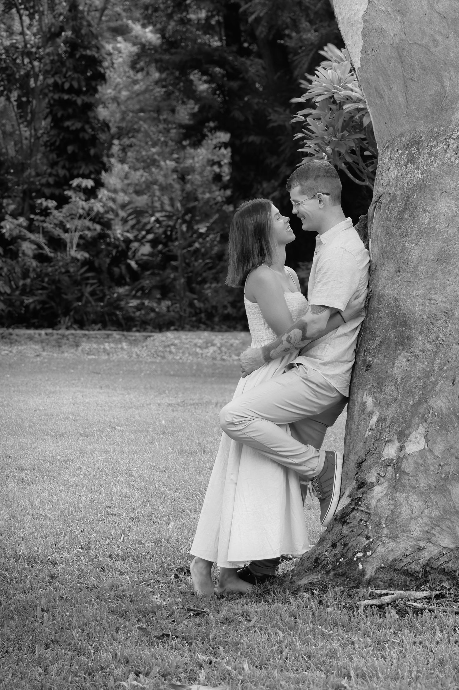 A romantic black and white photo sequence shows a couple sharing tender moments against a tree in a grassy field.