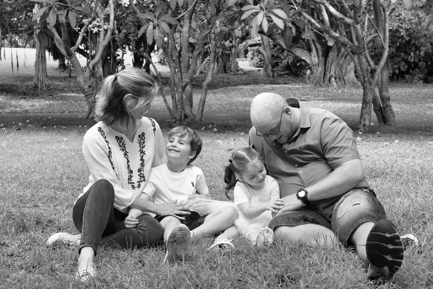 Family group relaxing together on grass during an outdoor photo session.