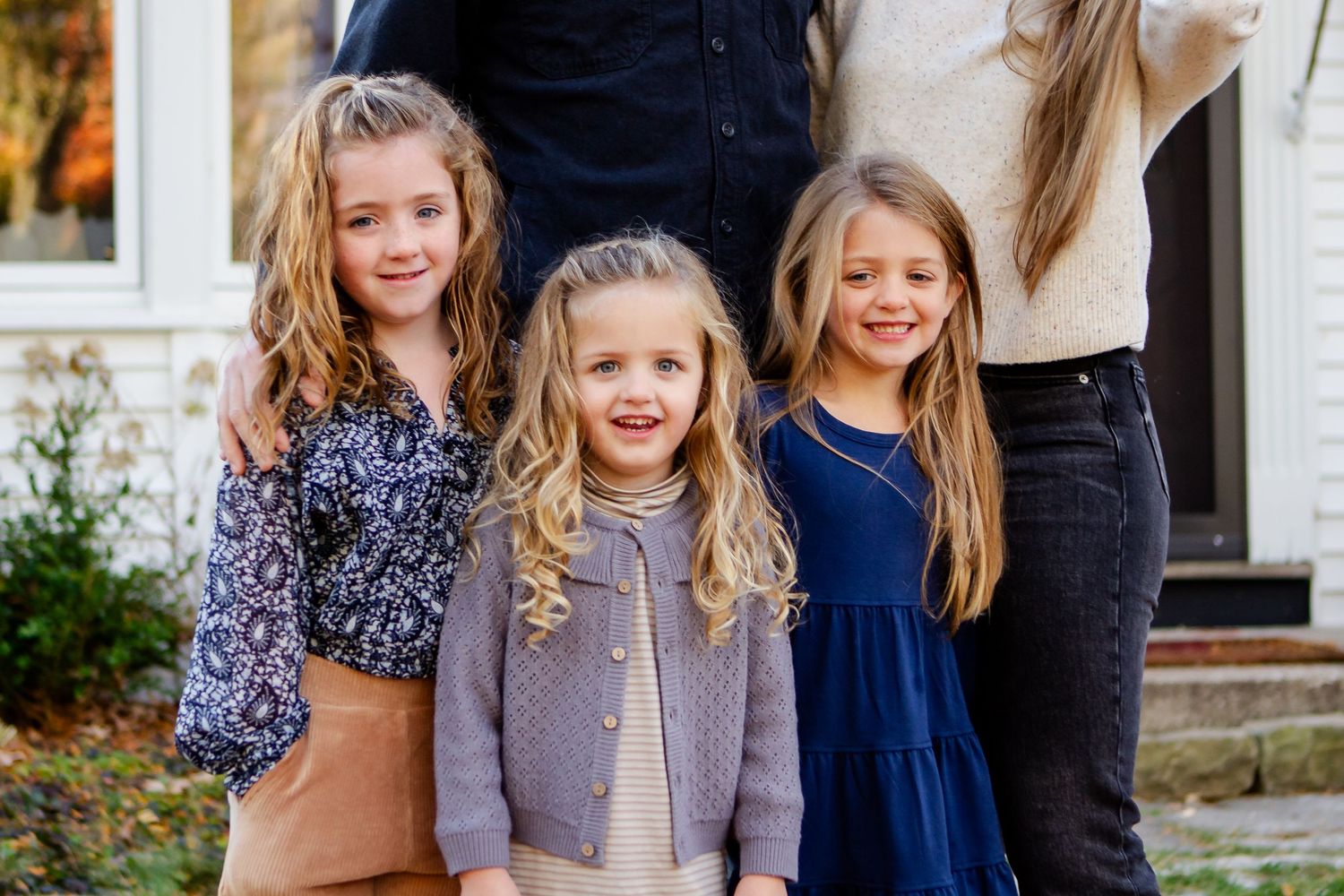 Family members in coordinating navy and gray outfits pose together for outdoor autumn portraits during Delafield family session
