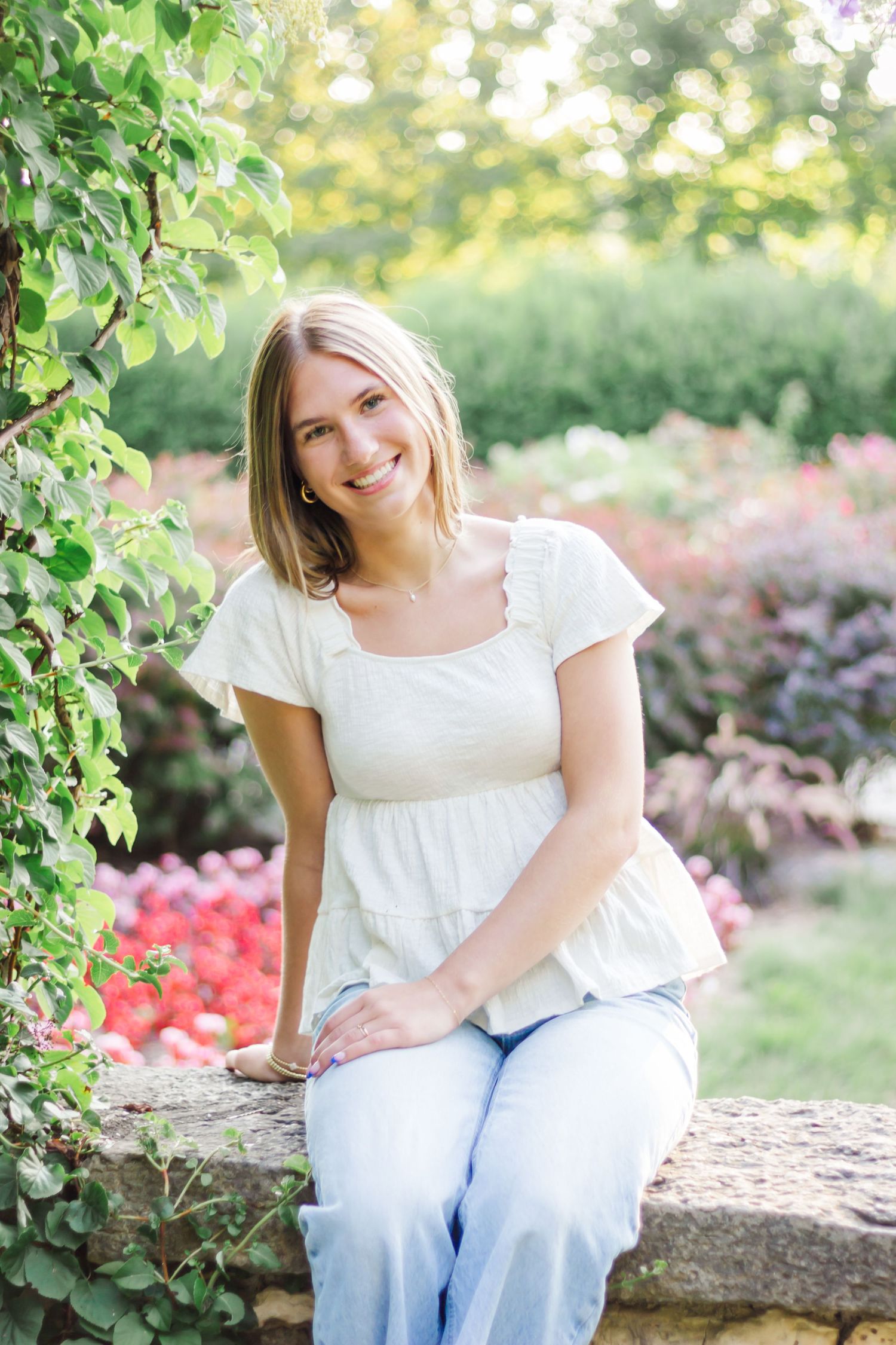 A garden portrait on a stone wall surrounded by colorful summer blooms.