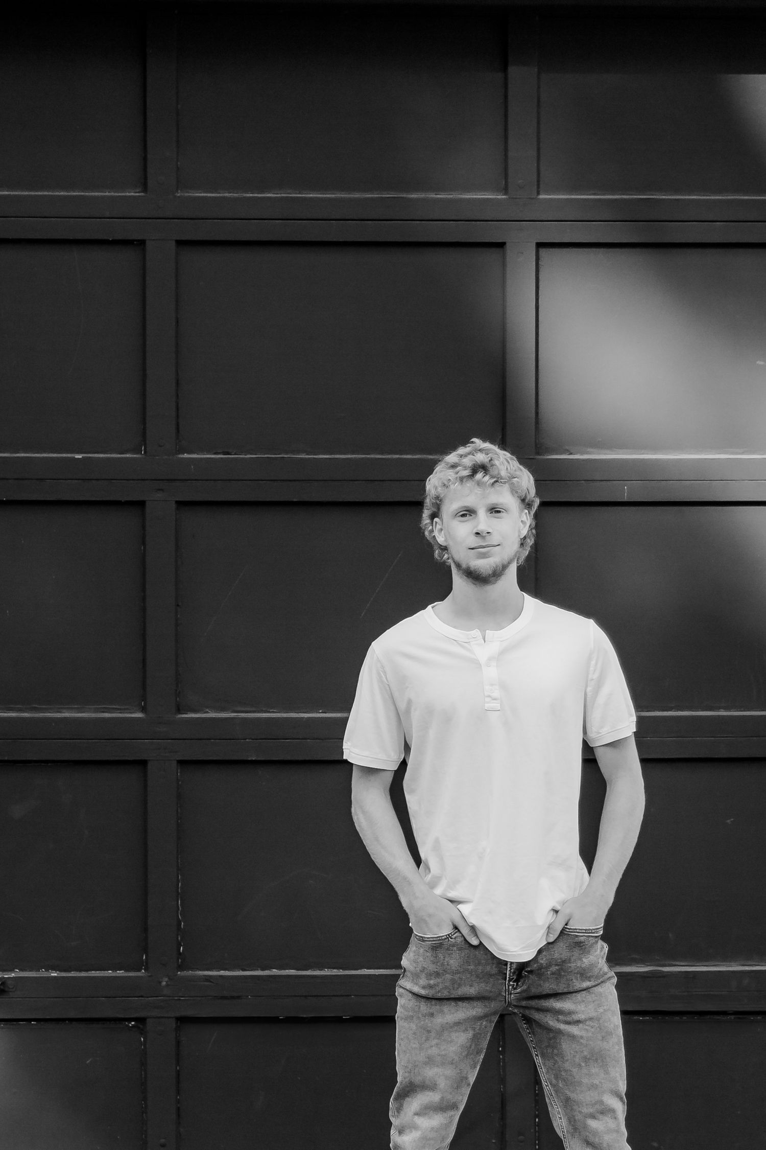 Black and white portrait against dark wall showing person in white t-shirt and jeans in different poses during a Michigan senior shoot