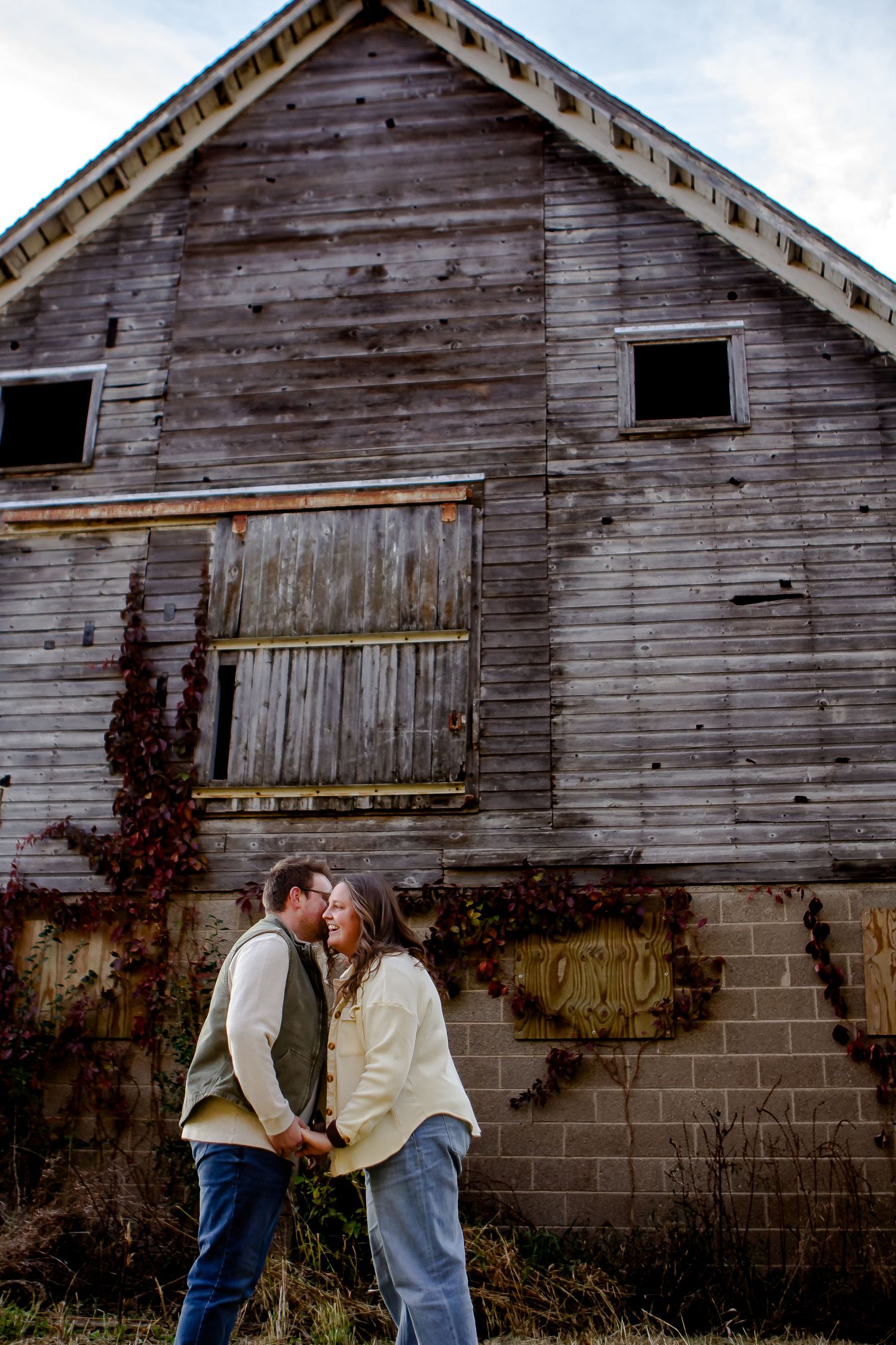 A couple kisses in front of a barn during fall photo session in Oconomowoc