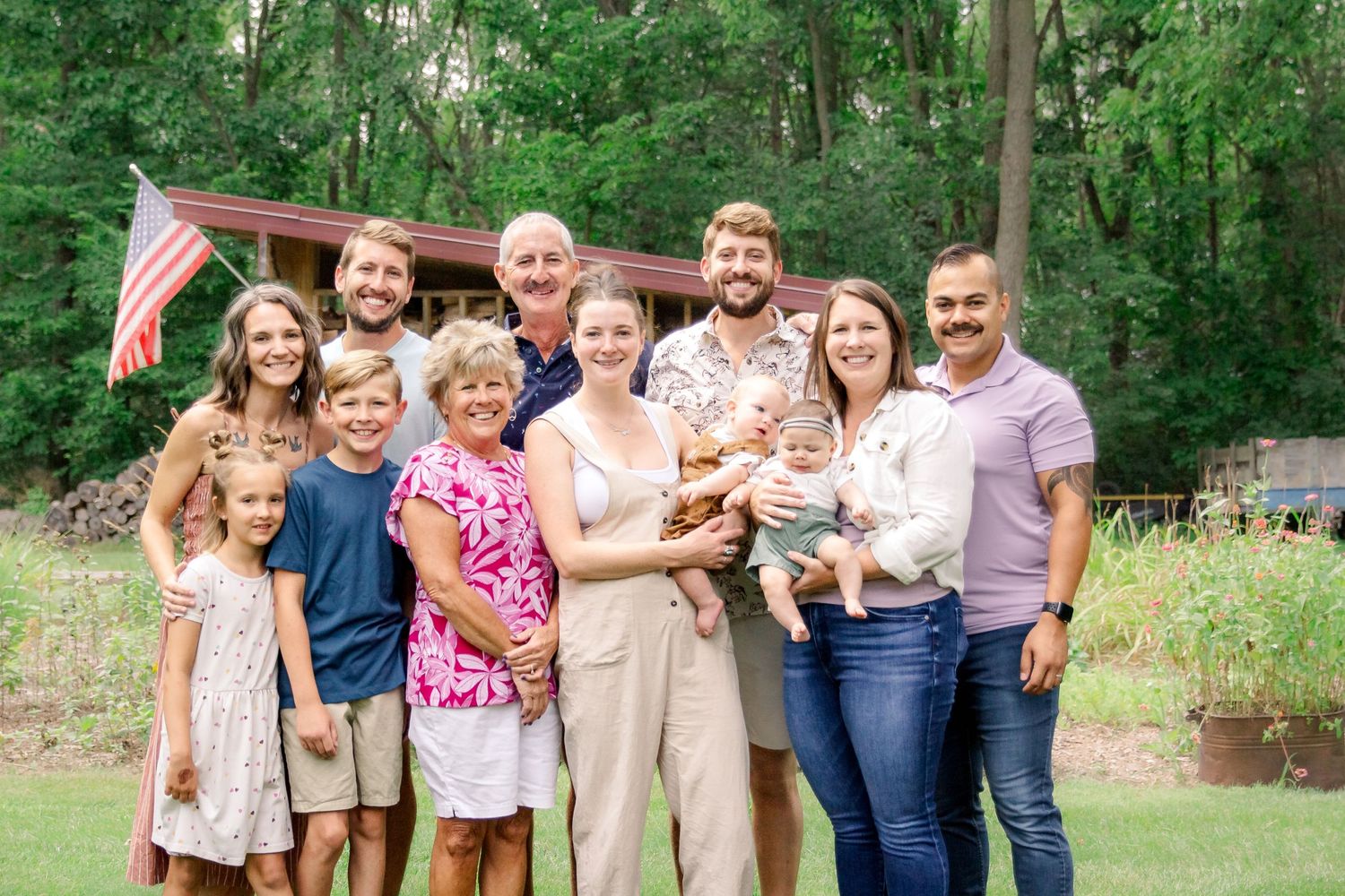 A group of people wearing casual attire pose together outdoors in a green natural setting at Delafield home session