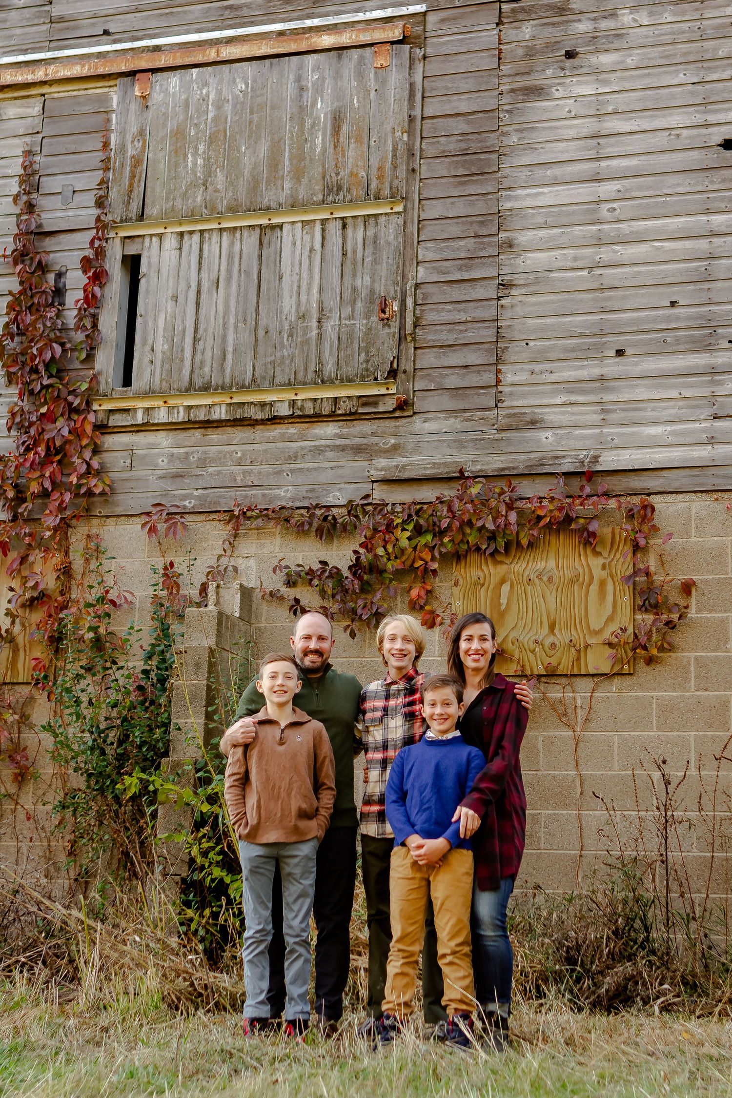 Family poses outside of barn during fall photo session in Oconomowoc