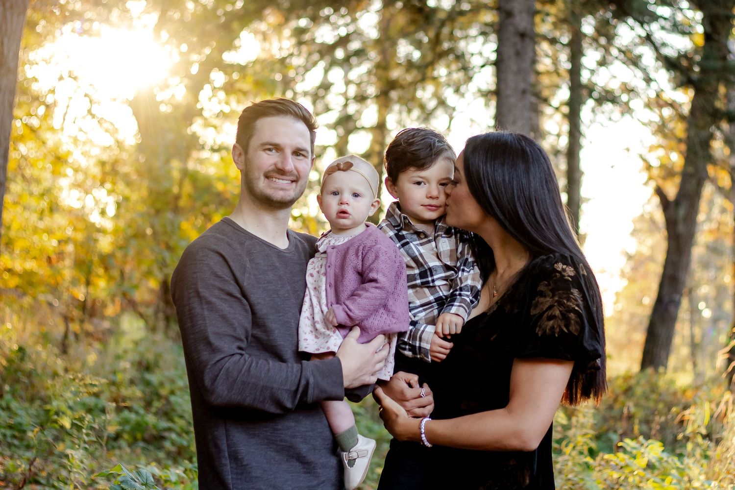 Family enjoys golden sunset in autumn park during outdoor photo session.