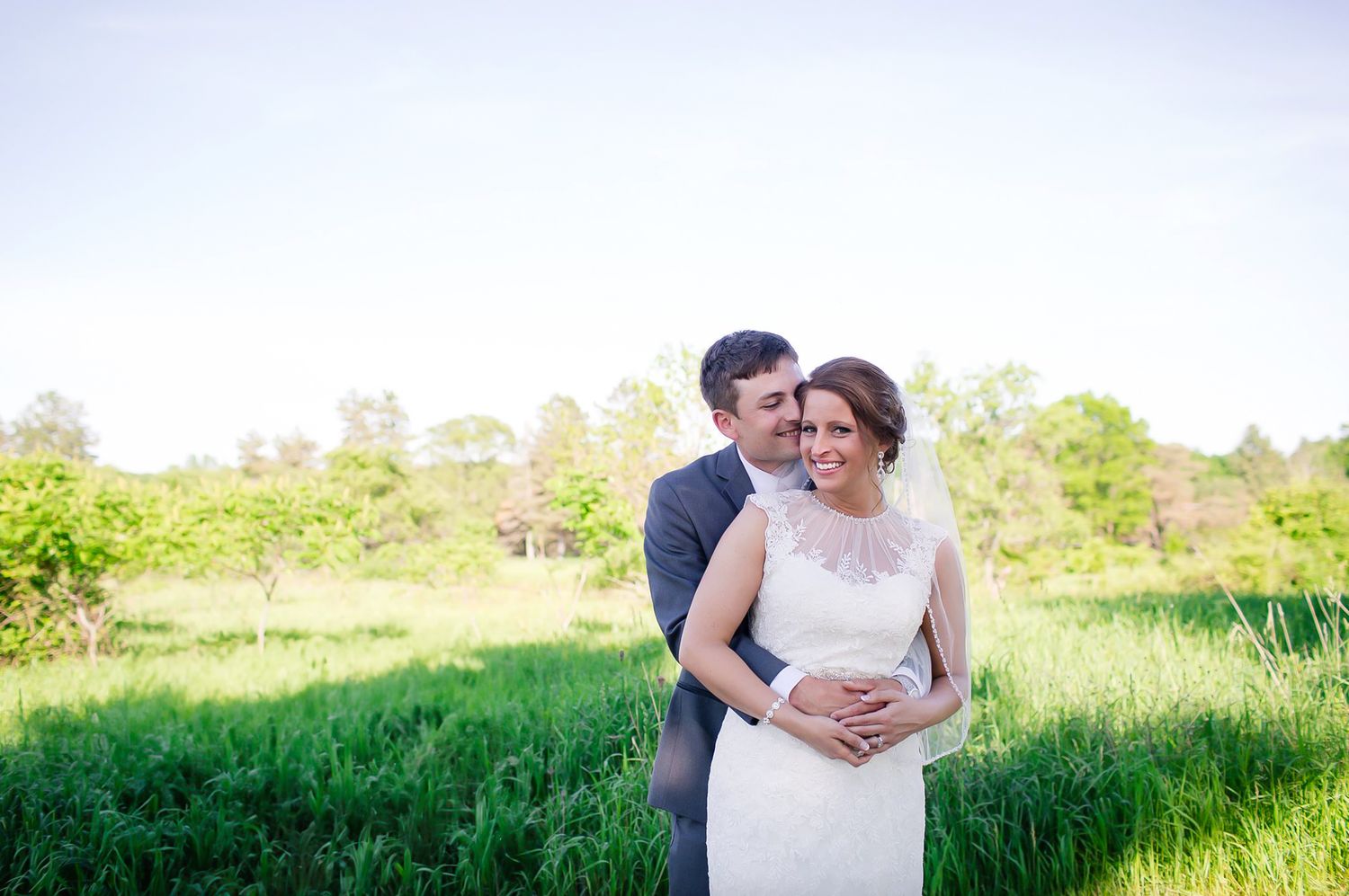 A couple shares a romantic moment together in a lush green meadow during golden hour taken by Wisconsin wedding photographer Megan Manne