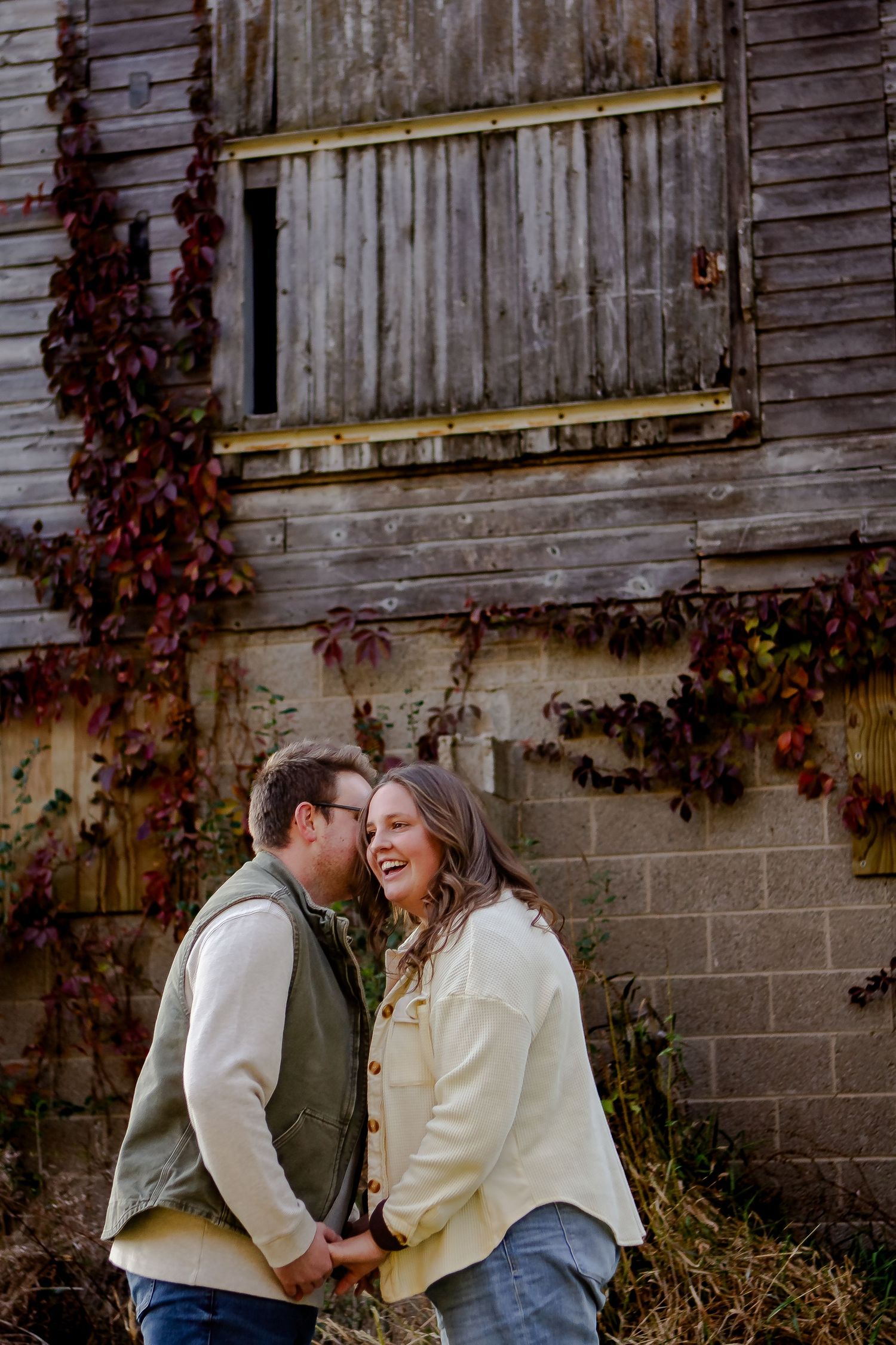 A man whispers into his wife's ear during fall photo session in Oconomowoc