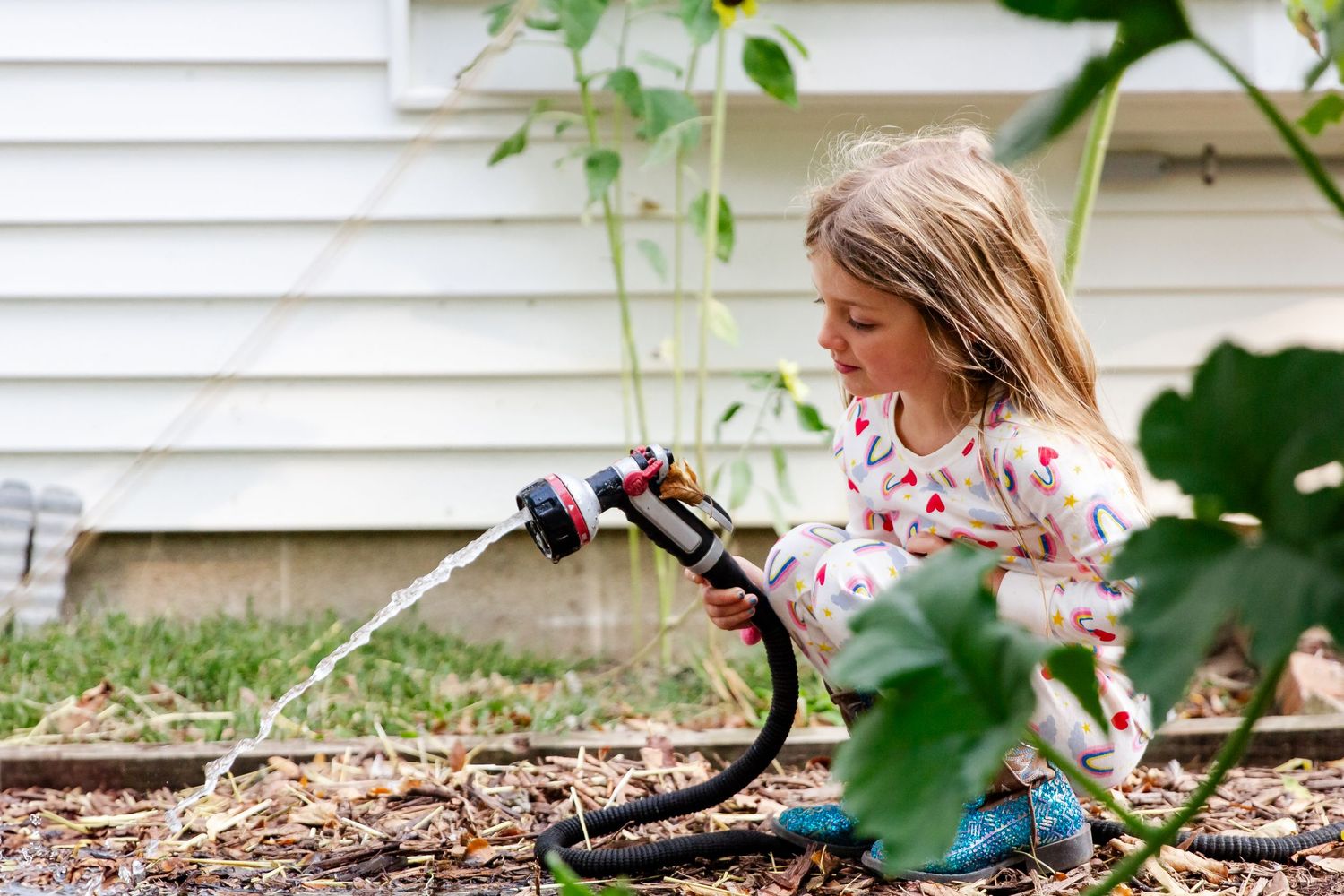 A child plays in a garden with fallen autumn leaves while wearing a pink and gray striped sweater at Delafield home session