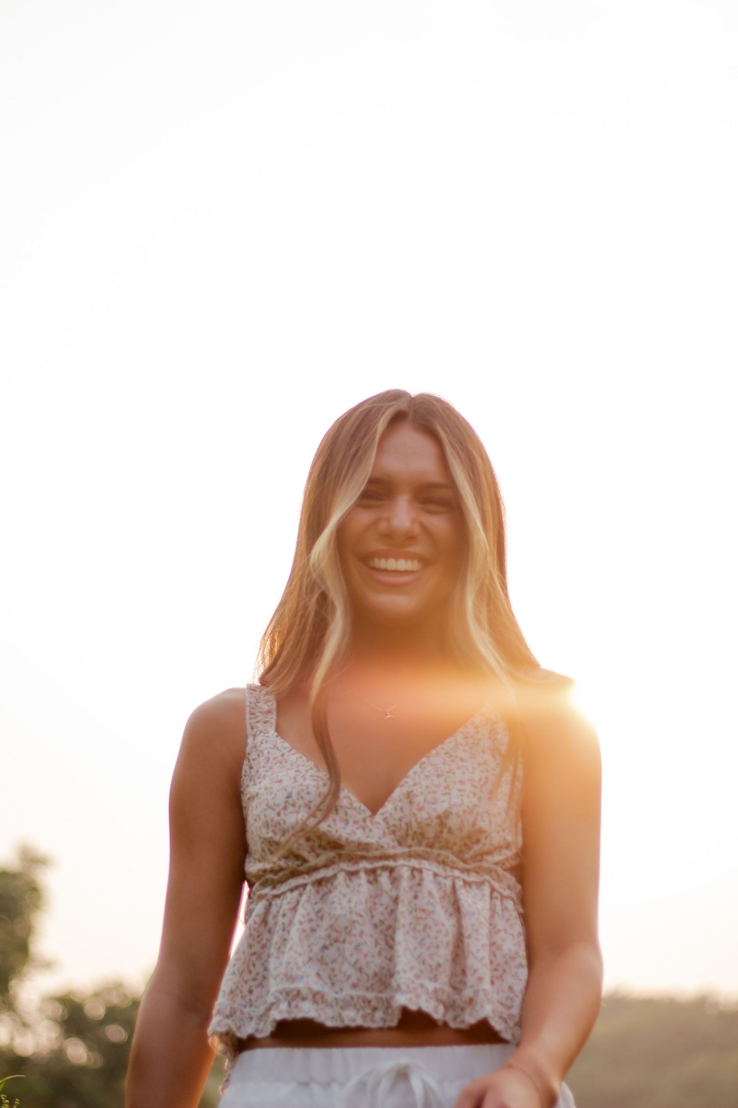 Sunlit portrait in white lace dress during golden hour outdoors.