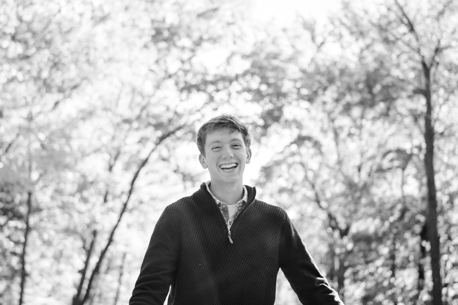 A boy smiles with trees in the background during his Hartland senior session