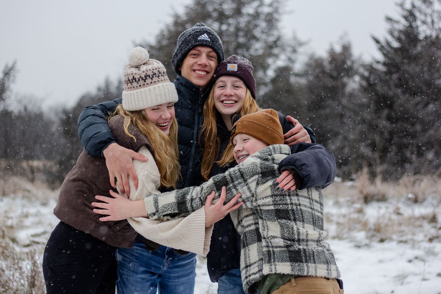Friends sharing laughter and hugs while enjoying a snowy winter day outdoors.