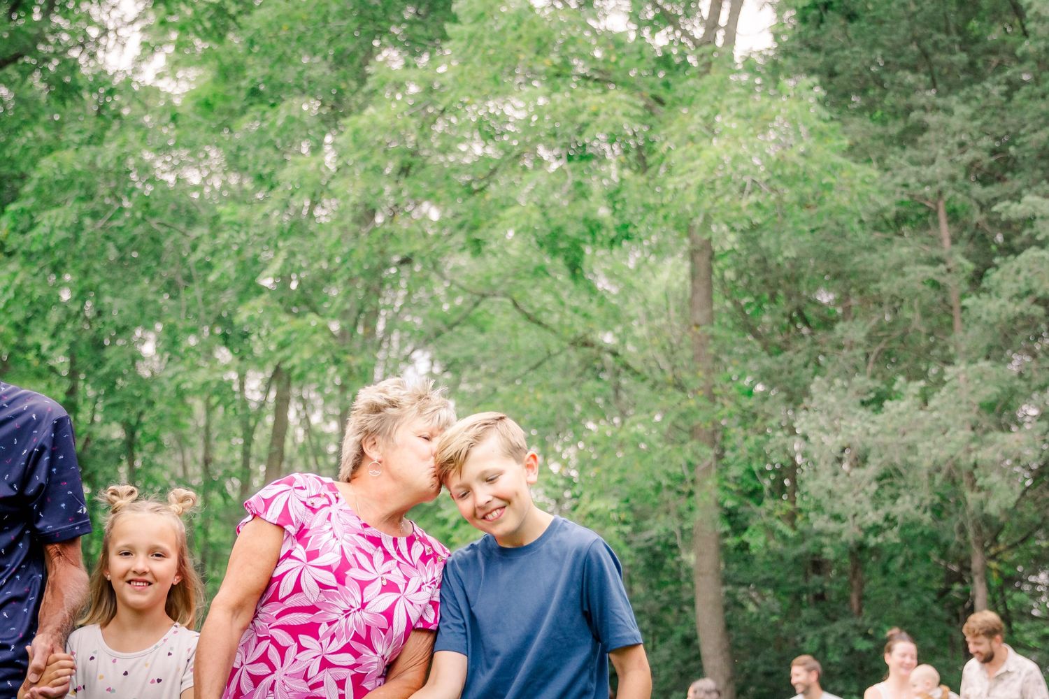 A family enjoys a playful moment together in a lush green forest setting during a photo session at Delafield home session