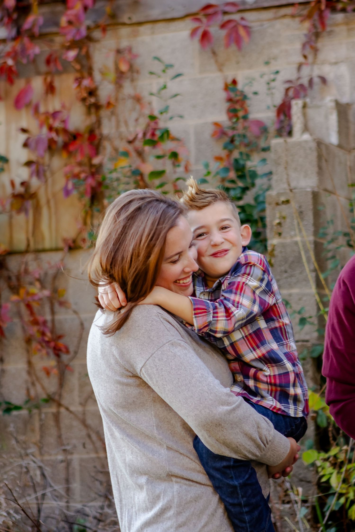 Family members embracing and laughing against autumn-colored wall backdrop.