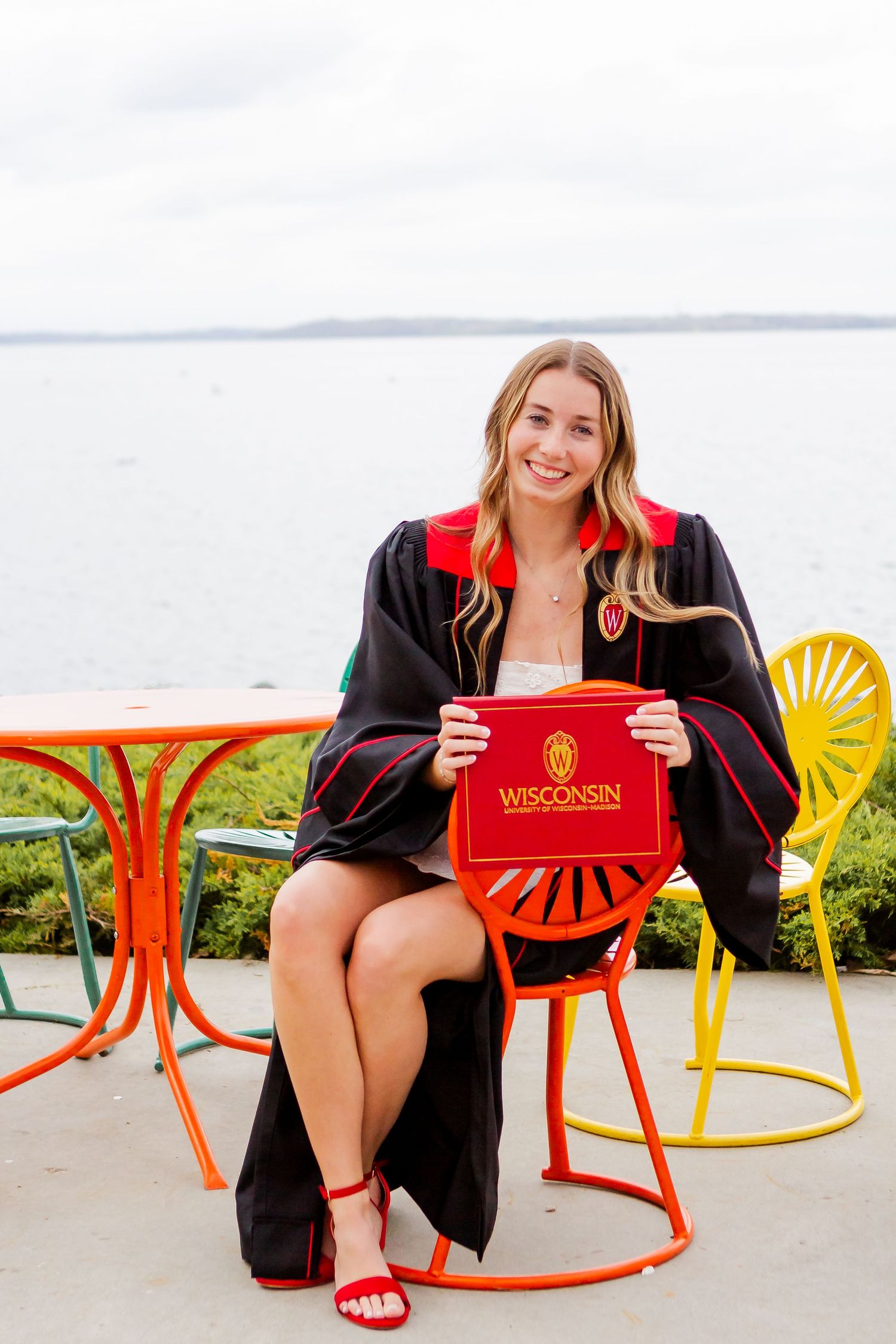 Graduate relaxing in colorful terrace chairs by the waterfront.