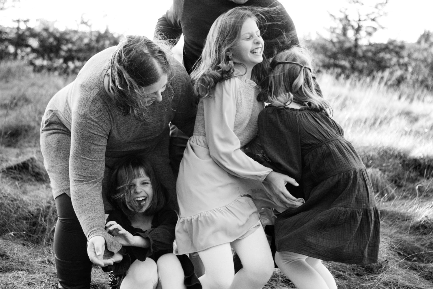 A series of black and white photographs showing tender family moments outdoors in a natural setting at an Oconomowoc family session