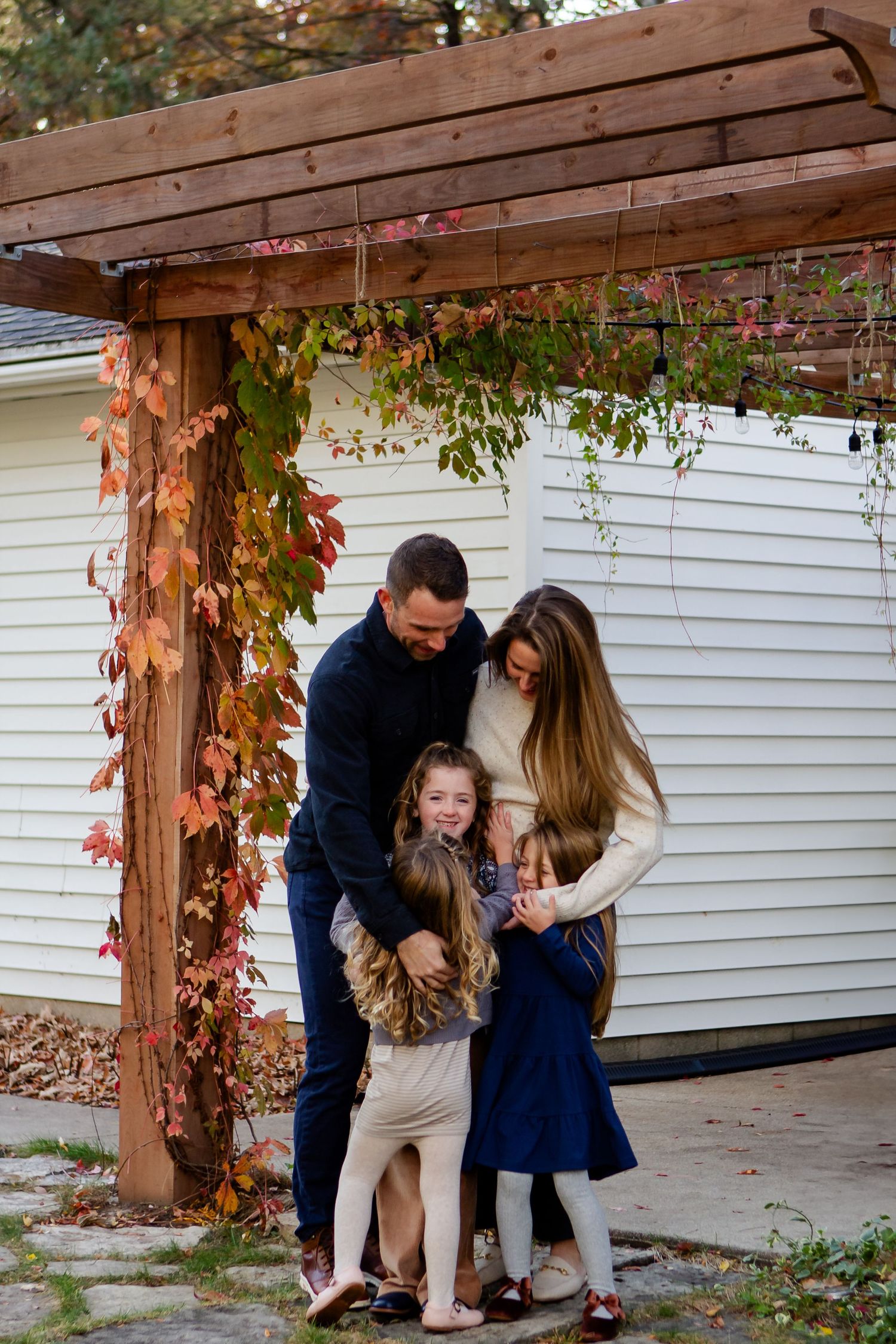 Family embraces each other outside of home during fall photo session in Delafield