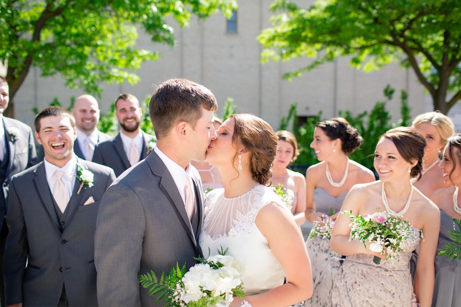A joyful wedding ceremony moment surrounded by smiling guests in an outdoor setting.